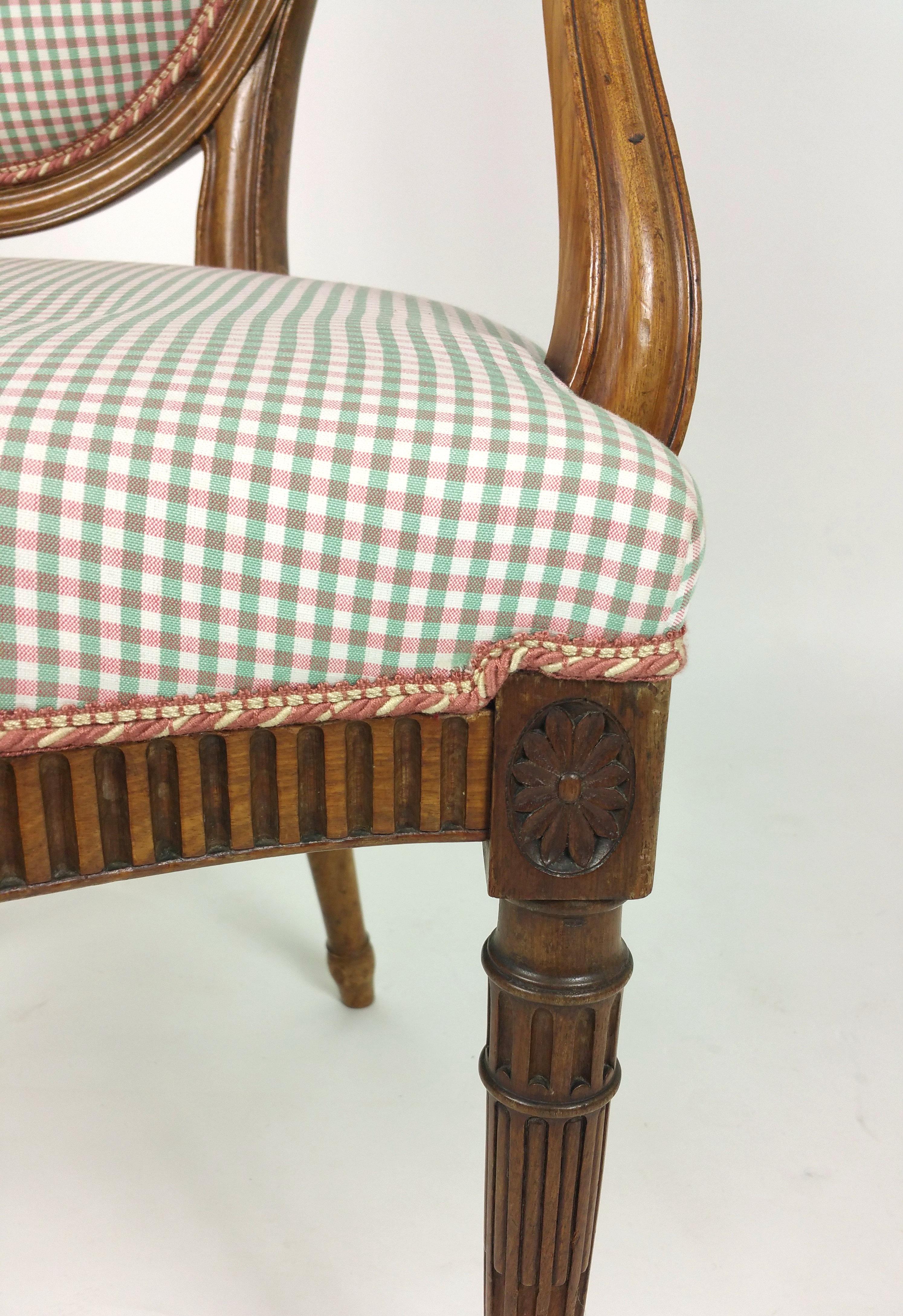 This 19th century Hepplewhite design carved walnut elbow chair carved with acanthus leaves supported on tapered turned legs and upholstered in a bright red and green small check fabric. It measures 23 ¼ in – 59 cm wide, 19 in – 48.2 cm deep and 37