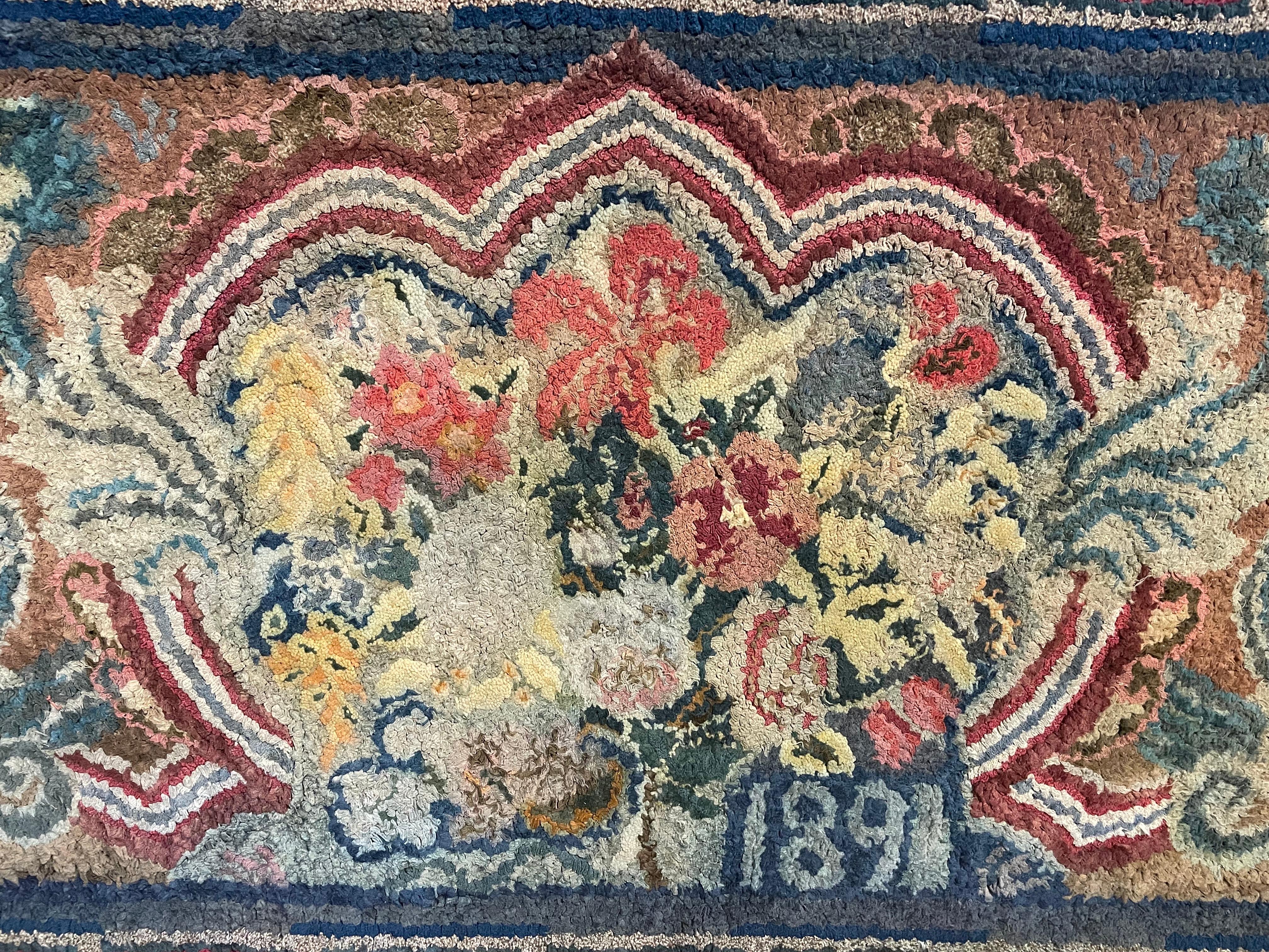 Lovely 19th century hooked rug with black braided border surrounding rug with vibrant red and teal highlighted Greek key border. Inset blue striped border around central floral medallion outlined by a striped arch and flanked by leafy arabesques.
