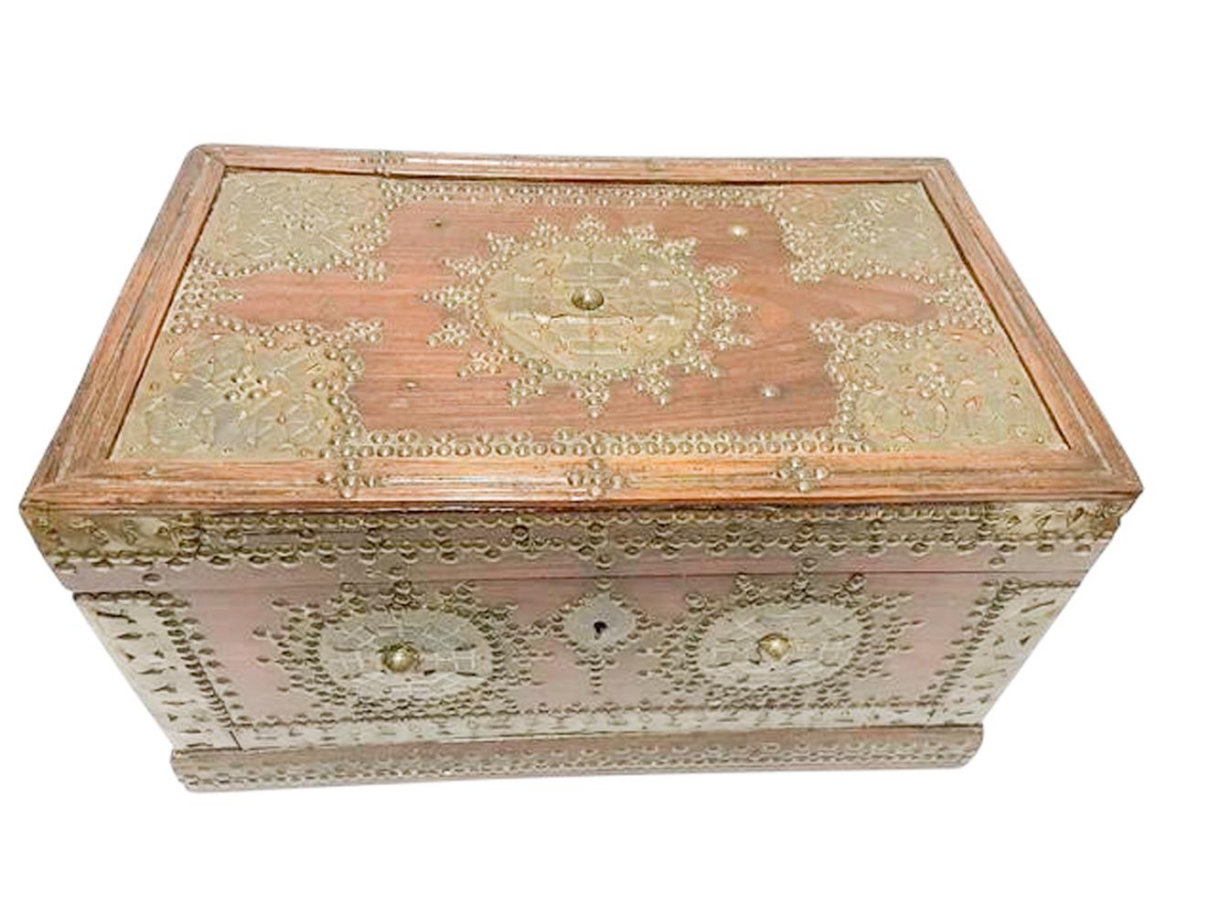 Indian teak work or stationary box with brass tack and applique decoration on the top and sides and fitted with brass lift-handles. the interior fitted with lift out trays and open compartments. 