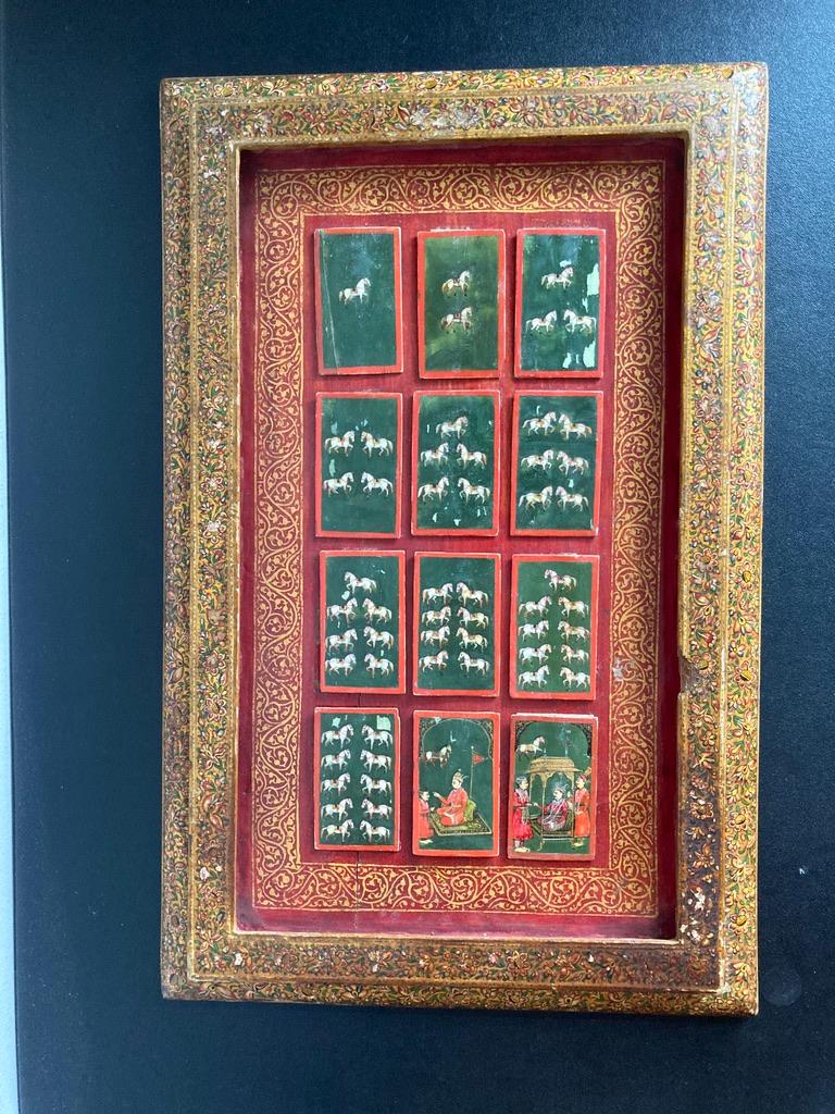 A rare set of 12 Mughal 'Ganjifa' bone playing cards, 10 of them hand painted as a suite with saddled white horses on a deep green ground with red border. The final 2 depicting a Prince and a Raja or King with attendants. The Prince seated on a