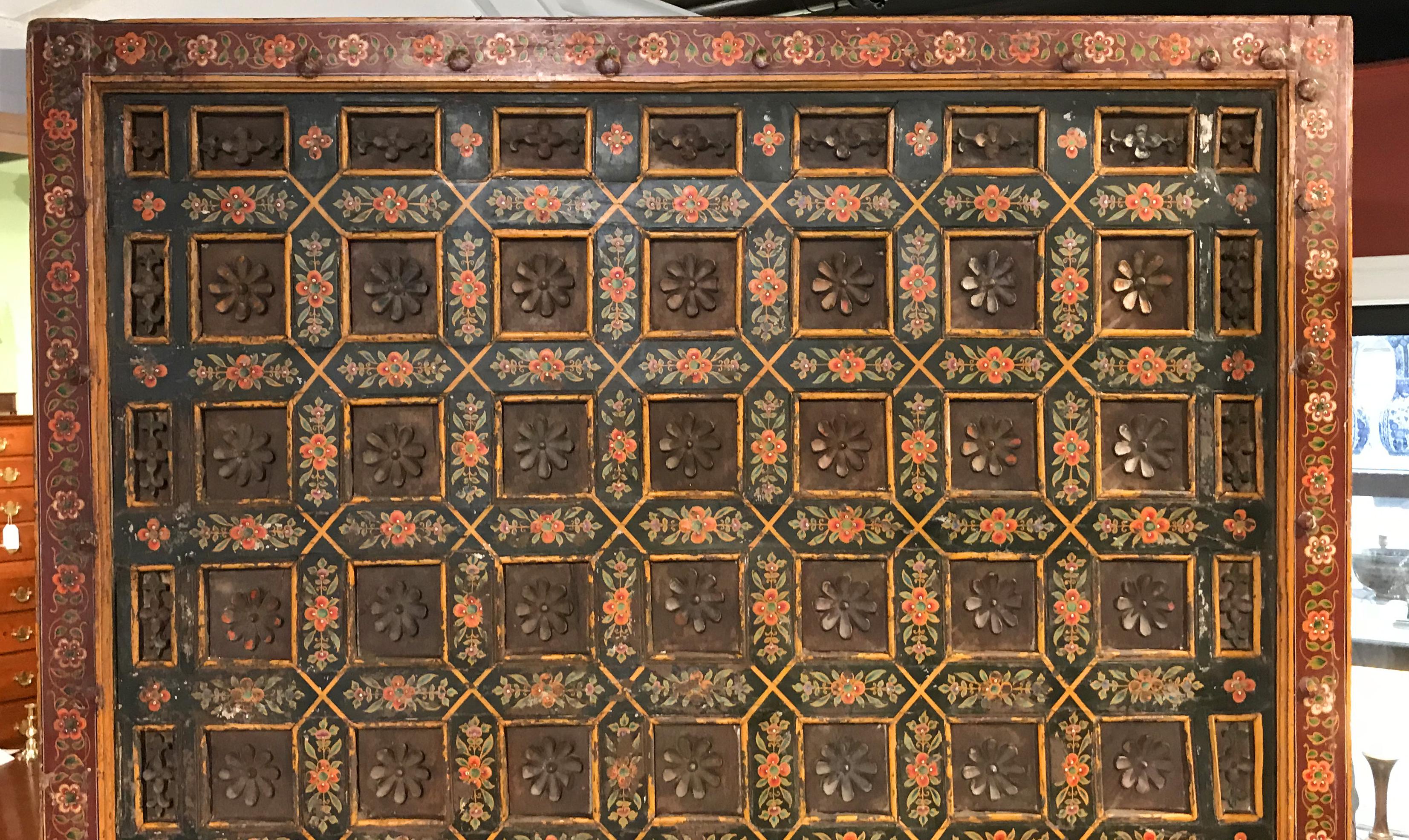 A fine example of an Indian polychrome carved wooden architectural element, most likely a ceiling panel, with repeating blocks with lotus blossom motif, accented by painted flowers in red and green, complimented by a red border with yellow