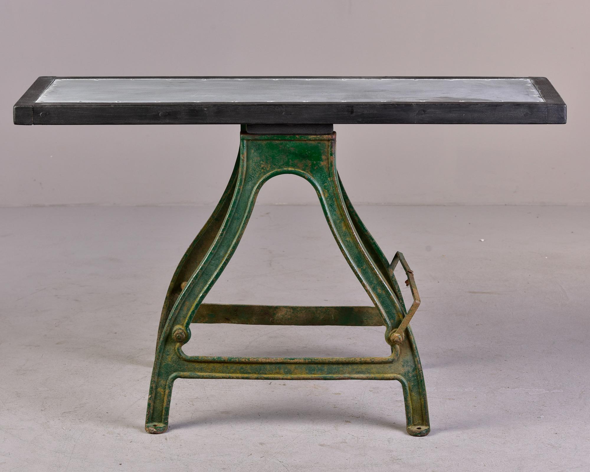 Found in England, this circa 1880s industrial work table has a heavy iron base with original green paint that shows some rust and patina. New wood, zinc-covered table top make this a unique console or functional narrow dining/breakfast table or