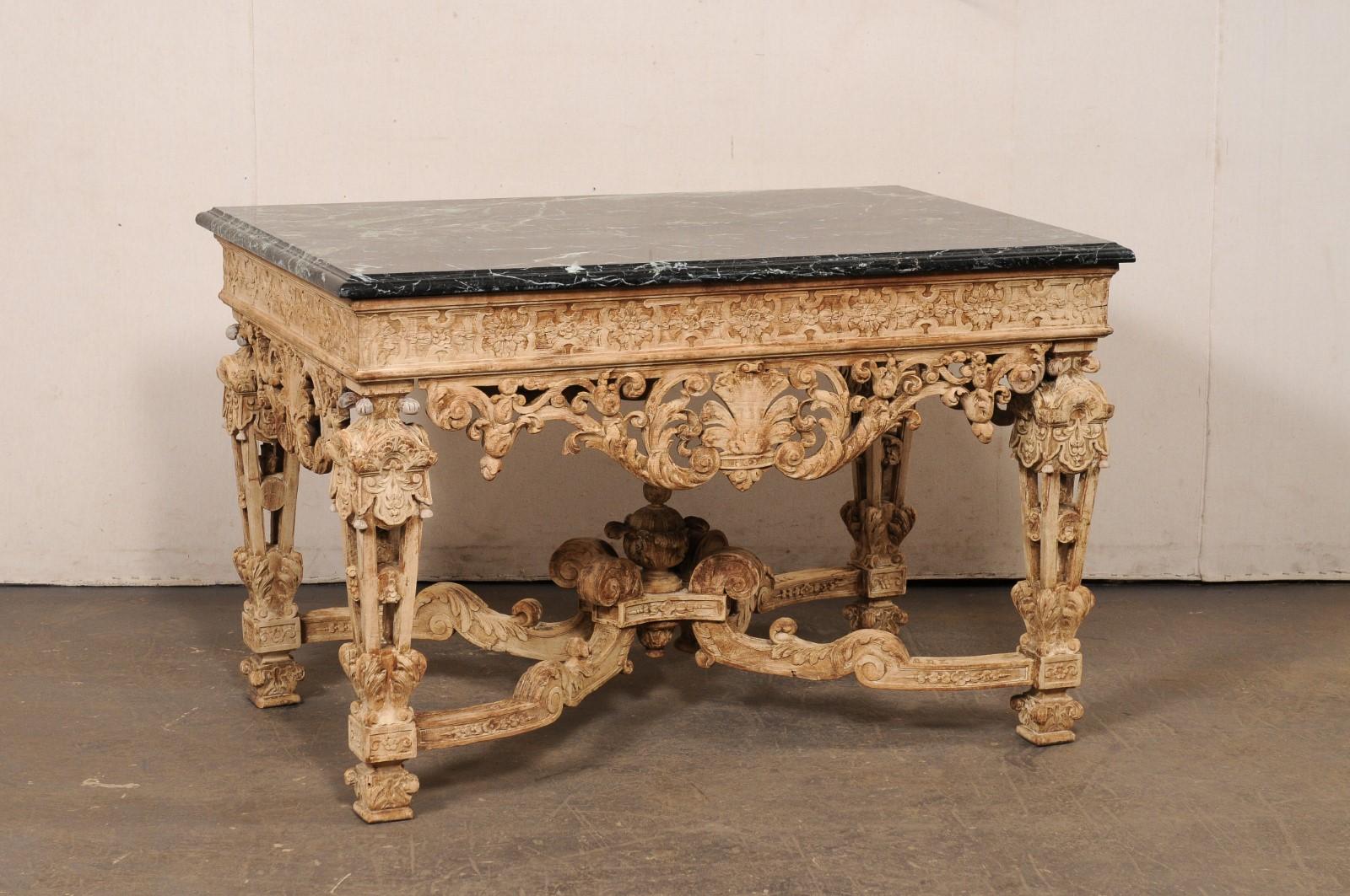 A French elaborately carved wood table with black/green marble top, from the 19th century. This antique table from France has a rectangular-shaped marble top, which rests atop the highly ornate carved wooden base (carved on all sides!) with apron