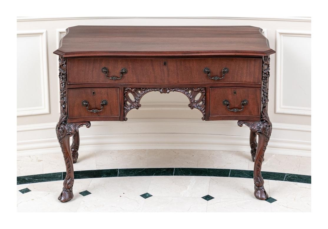 Scrivania irlandese di Giorgio III con foro per le ginocchia in mogano scuro con piano sagomato con bordo intagliato e angoli inclinati. Con un lungo cassetto a grembiule e due cassetti laterali che fiancheggiano il foro per le ginocchia intagliato