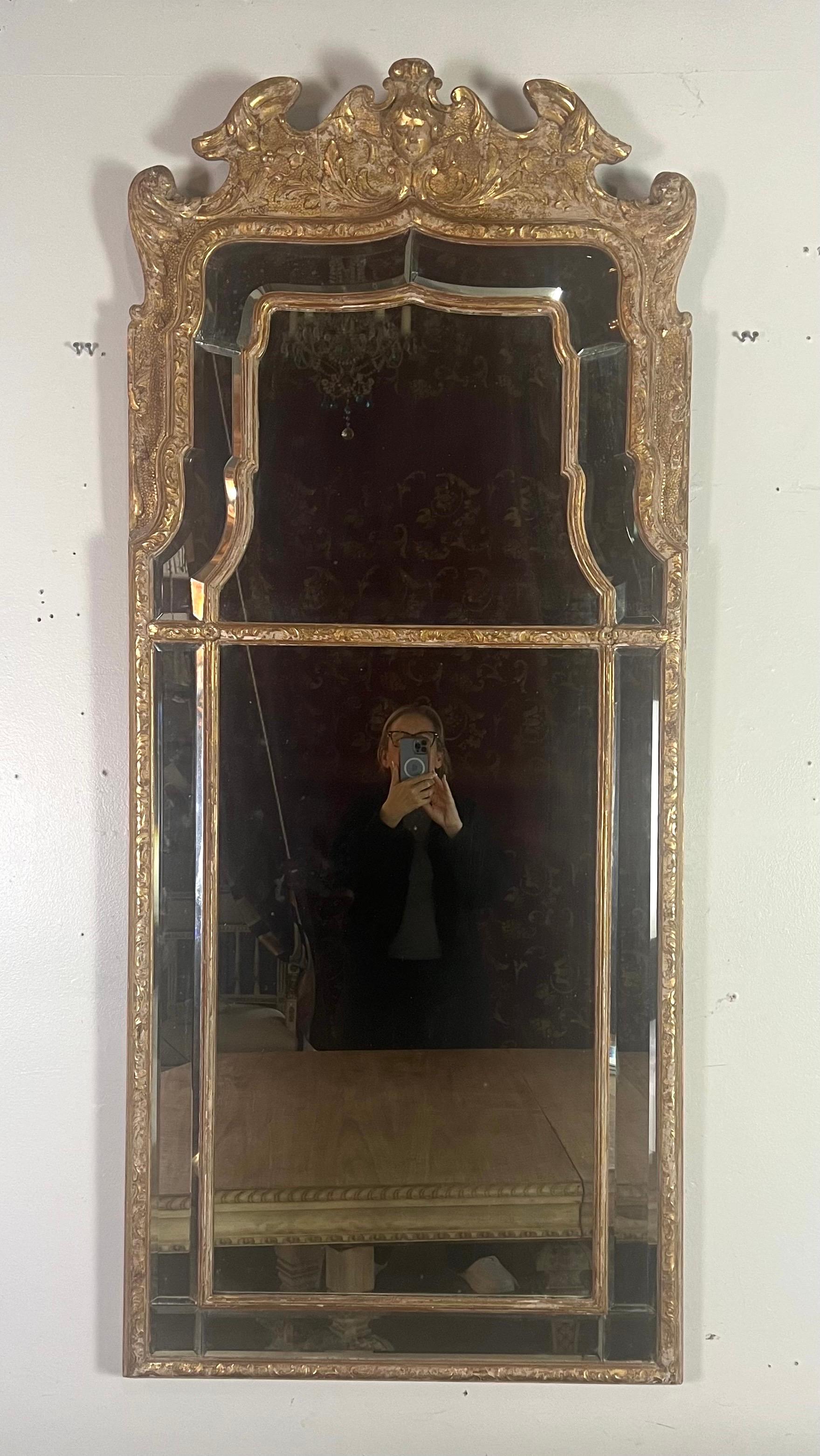 Specchio rettangolare in legno dorato in stile barocco italiano del XIX secolo con una cornice dal design elaborato.  La cornice presenta intricati intagli e dettagli ornamentali, in particolare nella parte superiore, dove sono presenti elementi