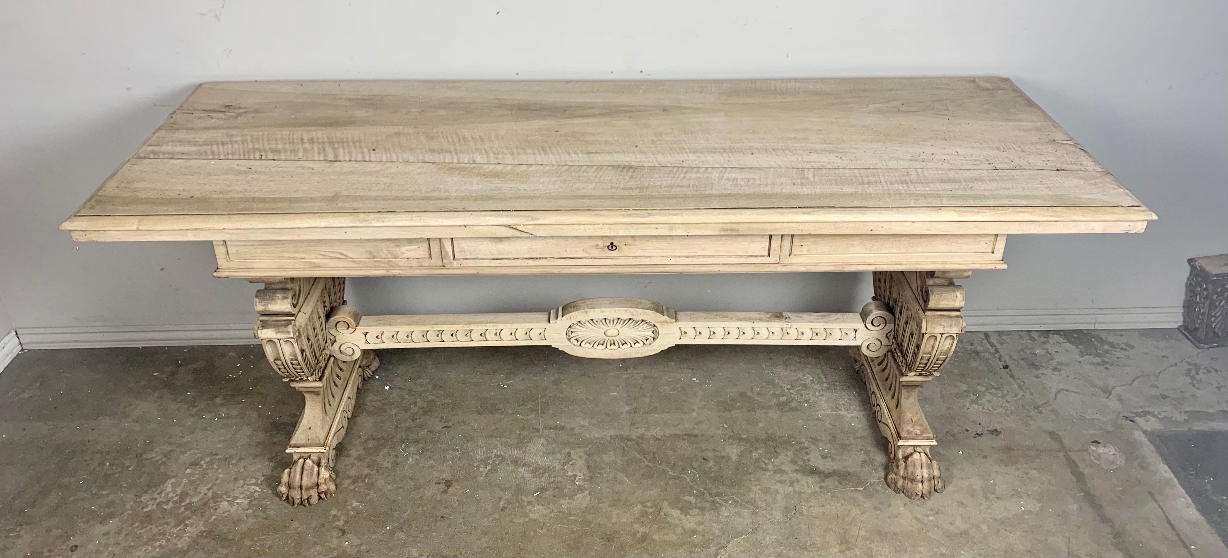 19th century bleached walnut trestle style table with two pedestals connected by a center stretcher. Single drawer for storage. The highly carved urn shaped pedestals are supported by carved wood lion feet. The center stretcher is also finely carved