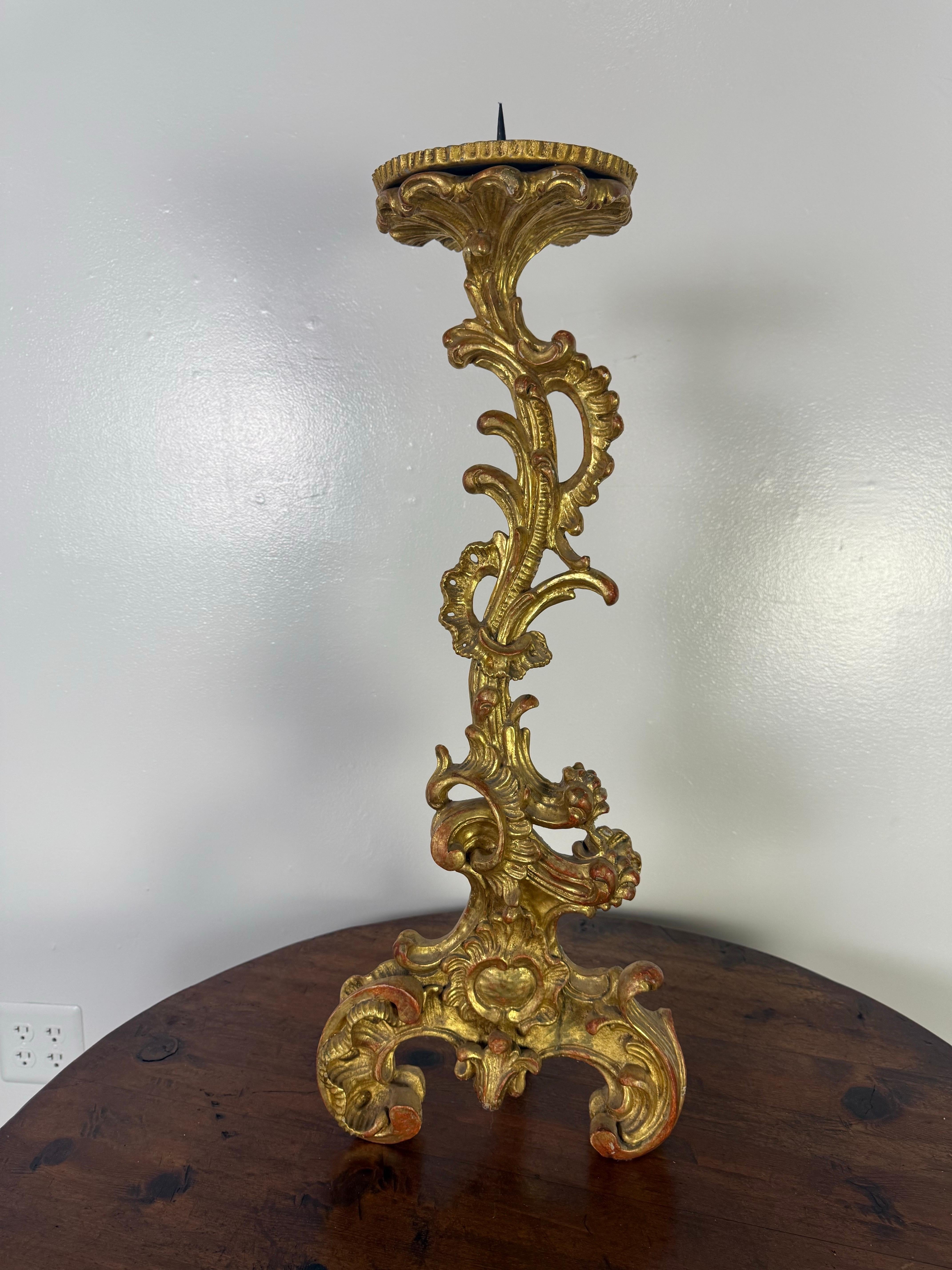 This striking 19th century Italian altar stick is a finely carved example of Baroque-inspired ecclesiastical art, rendered in richly gilded wood. Standing on a tripartite base with exuberantly scrolled feet, the piece features an undulating profile