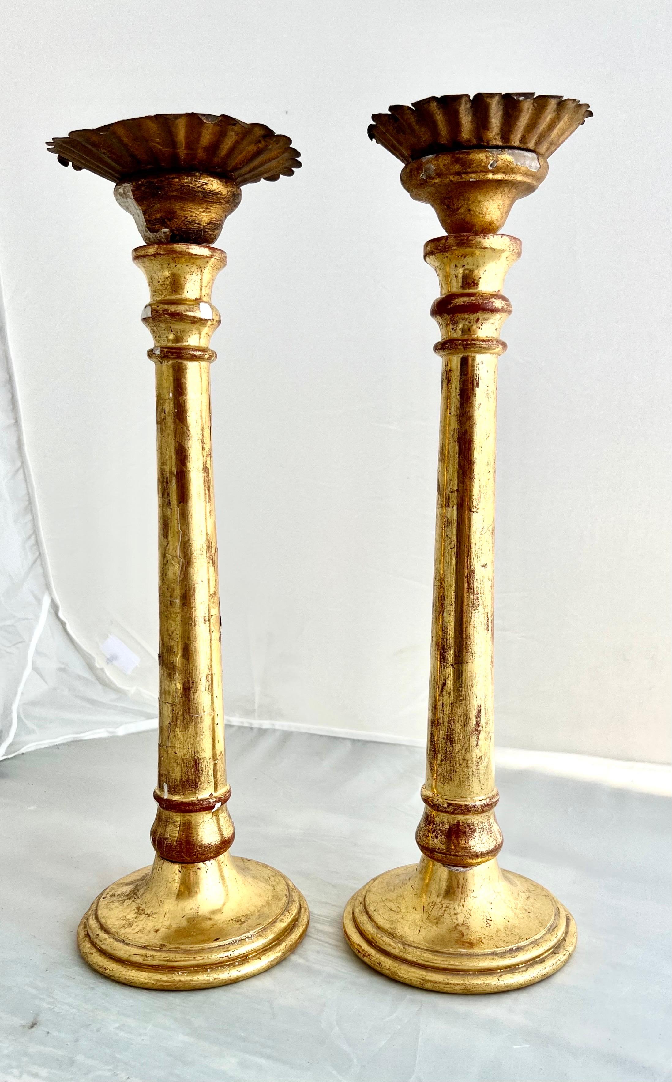 Water gilt Italian neoclassical-style candlesticks adorned with iron bobeches.   The water gilt technique imparts a lustrous and aged appearance, enhancing the overall neoclassical design.  These candlesticks, with their combination of materials,