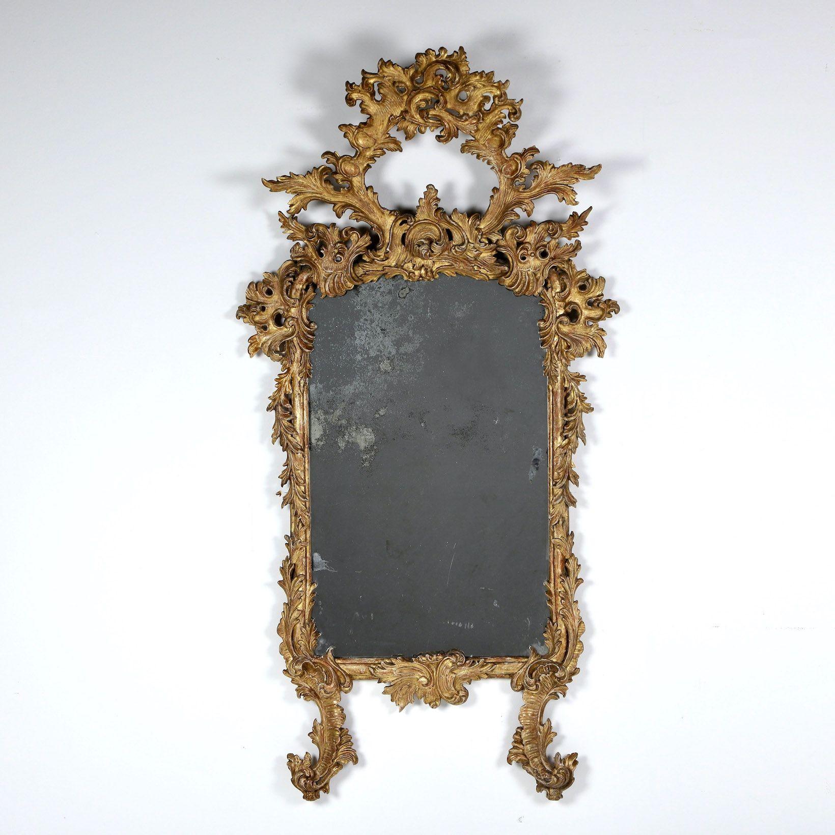 Feiner, schön gealterter, originaler Vergoldungsspiegel mit originaler Spiegelplatte im Stil des Rokoko mit fließendem, symmetrischem Blattmotiv, um 1820. Elegante Form, in Abschnitten geschnitzt.

Das Rokoko folgte auf das Barock und wird oft als