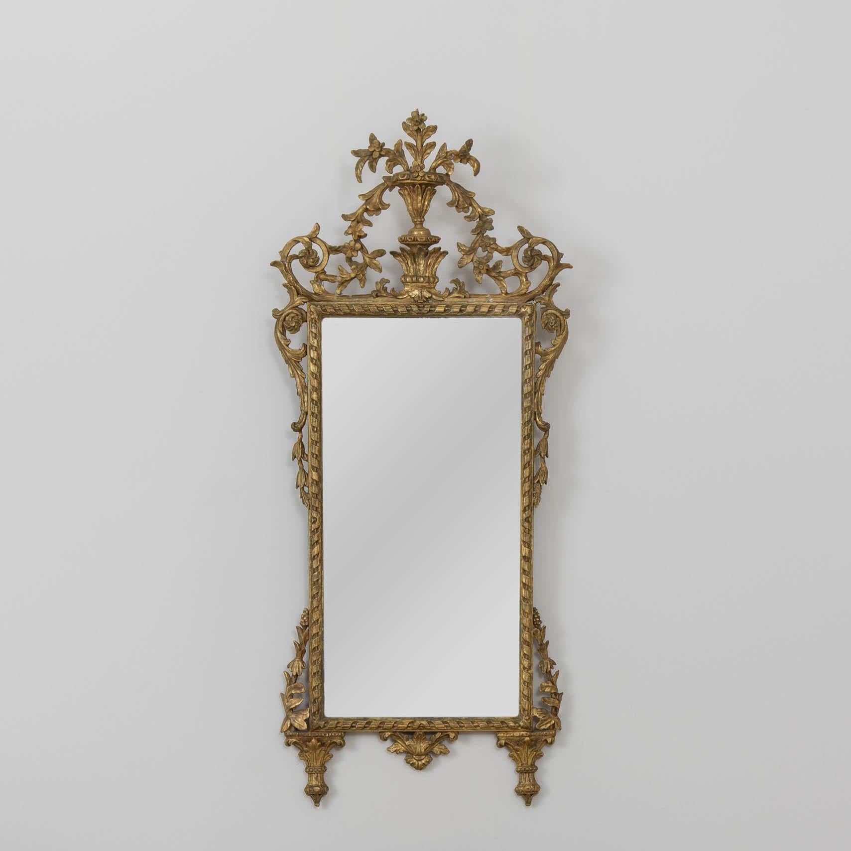 Elegante espejo italiano, finamente tallado con madera dorada original bellamente envejecida y placa de espejo original. Frontón de urna tallado con motivos florales y hojas.