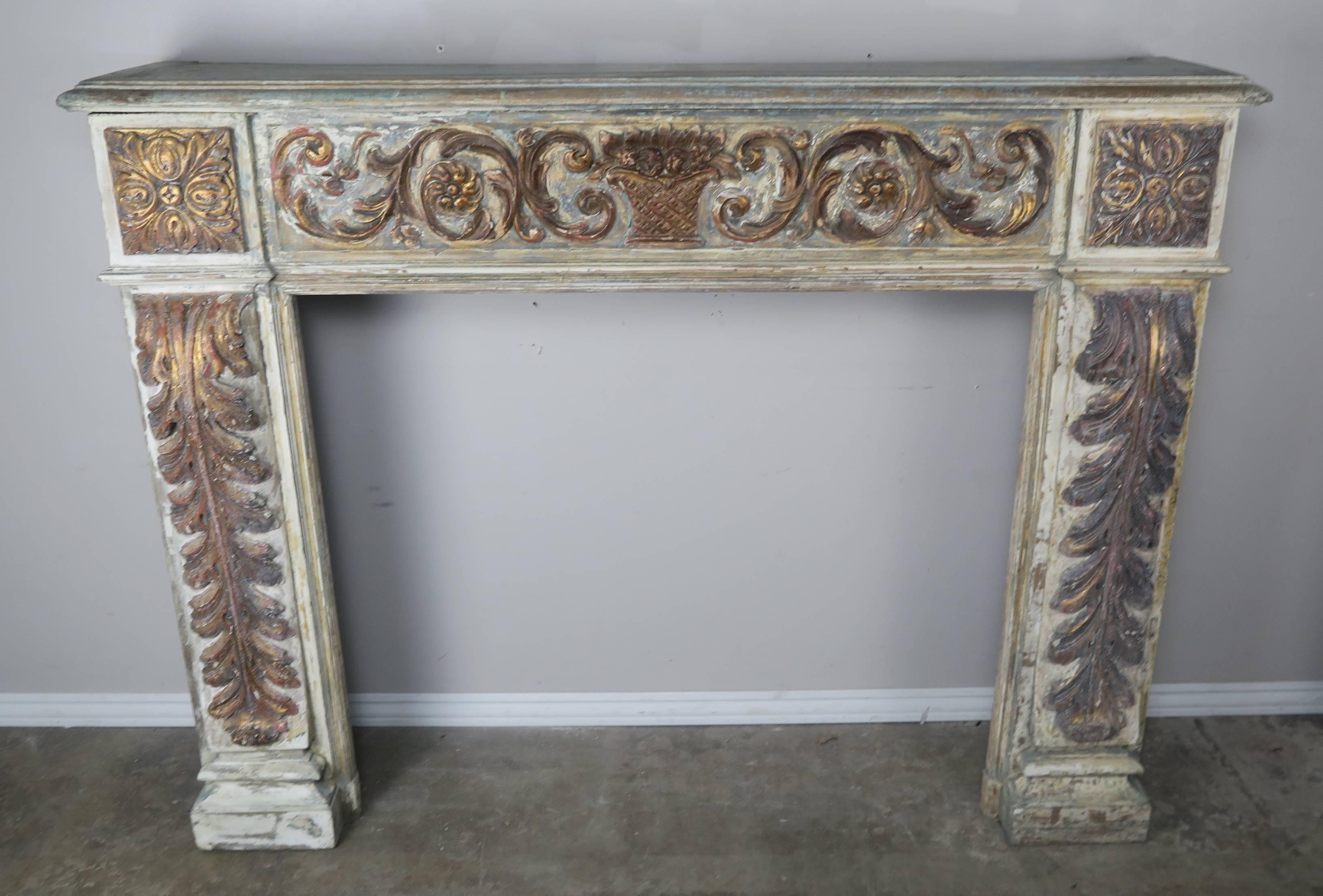 19th century Italian carved painted and parcel-gilt fireplace mantel. Detailed with a centre urn with swirling flowers and acanthus leaves throughout.
  