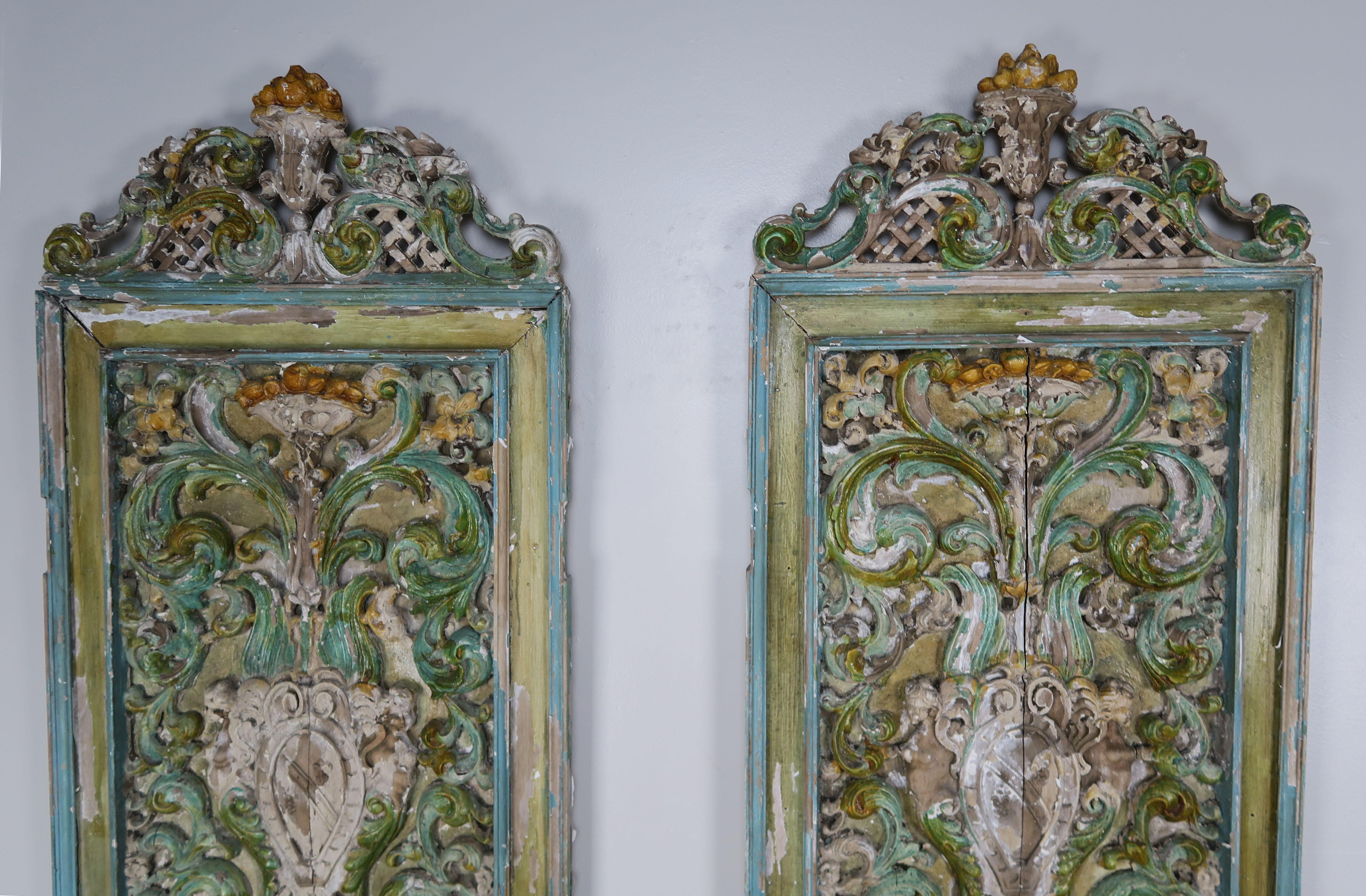 Pair of 19th century Italian carved and painted panels. The intricate carving depicts urns with swirling acanthus leaves throughout. Beautiful shades of greens, blues and golds. Ready to hang.
 