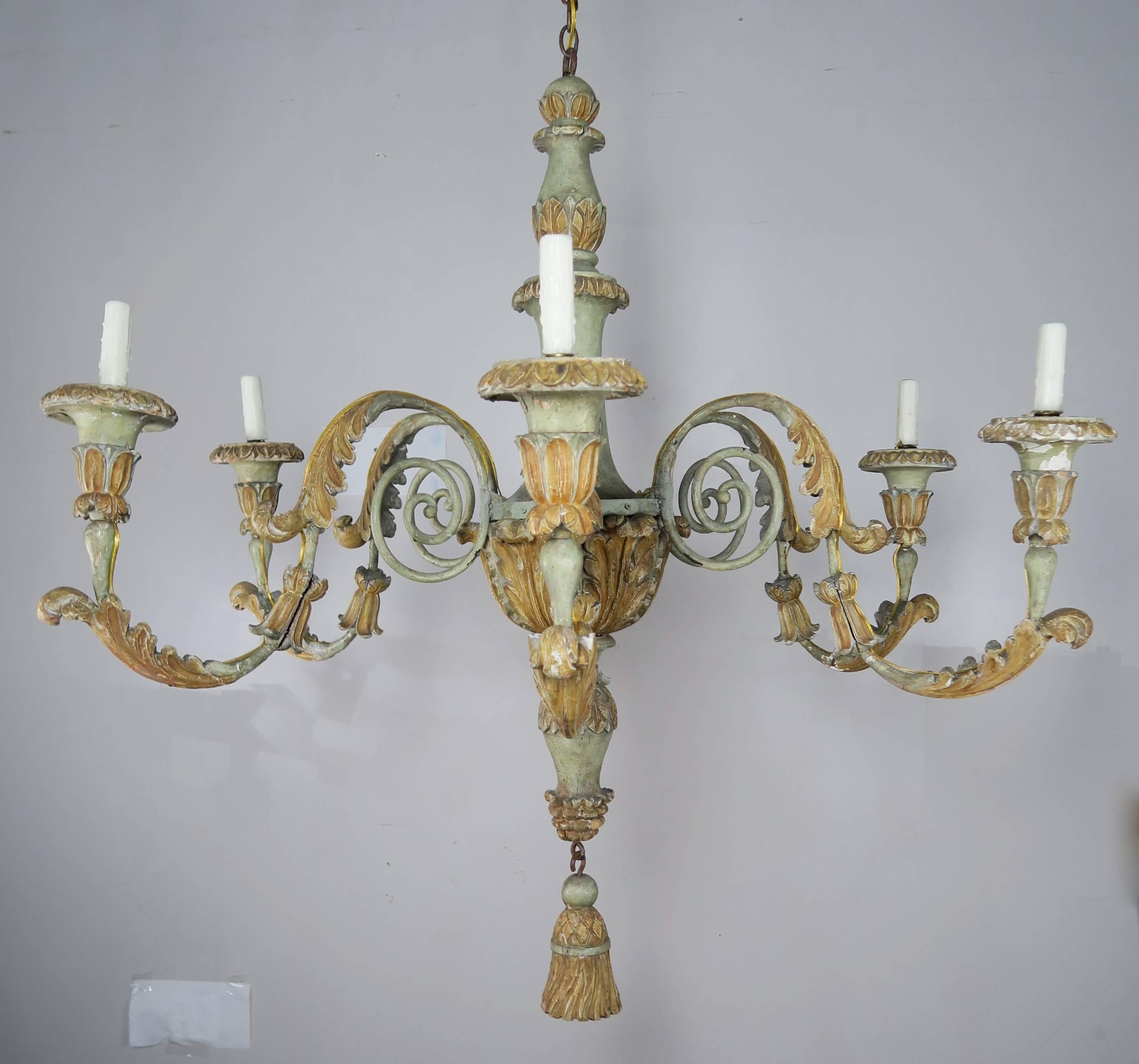 19th century grand scale Italian painted six-light wood and iron chandelier. The fixture has six scrolled iron arms with carved acanthus leaf detail on each. A large carved wood tassel hangs from the bottom. This chandelier has been newly rewired