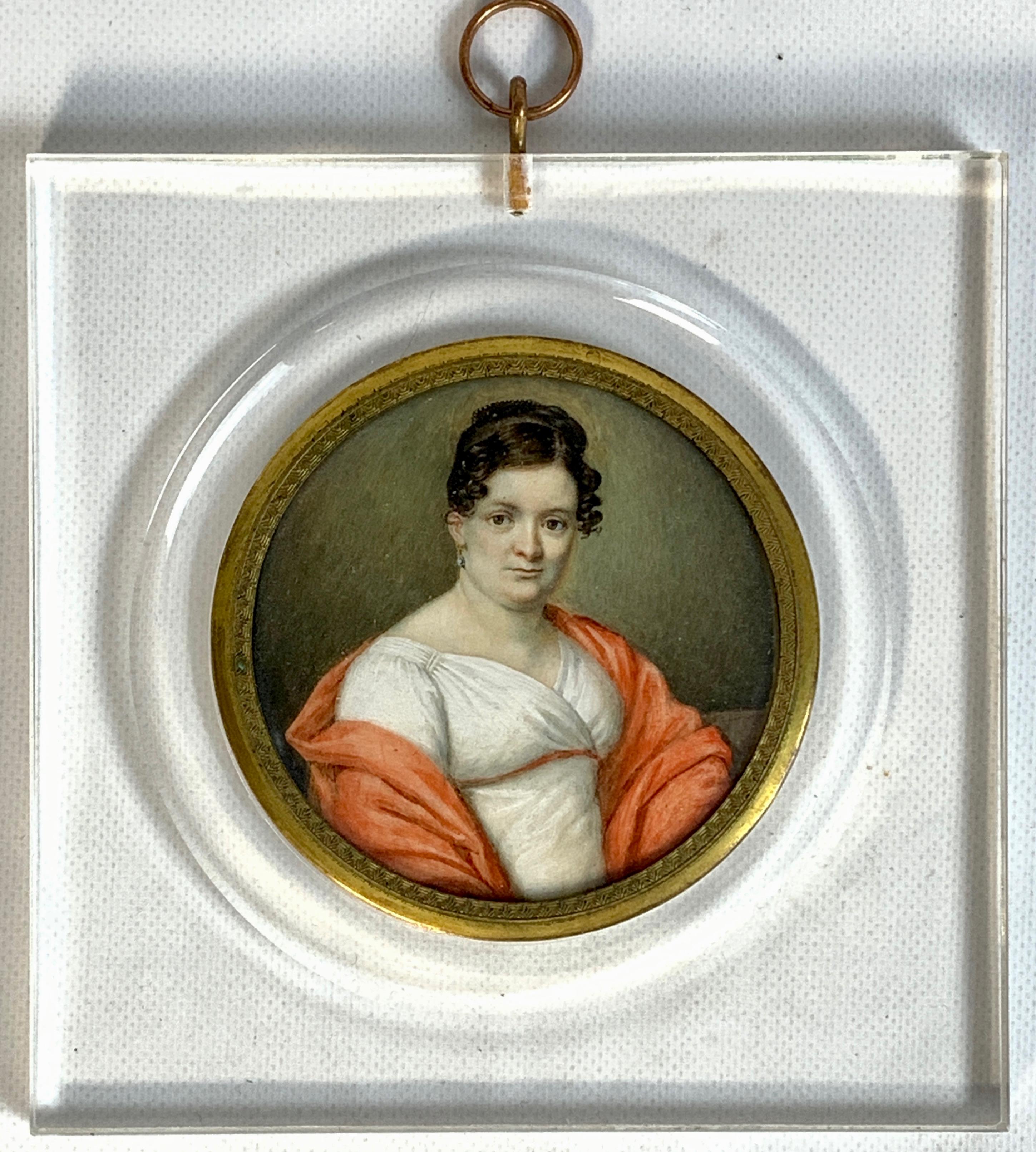 A beautifully painted early 19th century Italian portrait miniature of an elegant woman in white dress with coral shawl. Recently framed in Lucite frame.