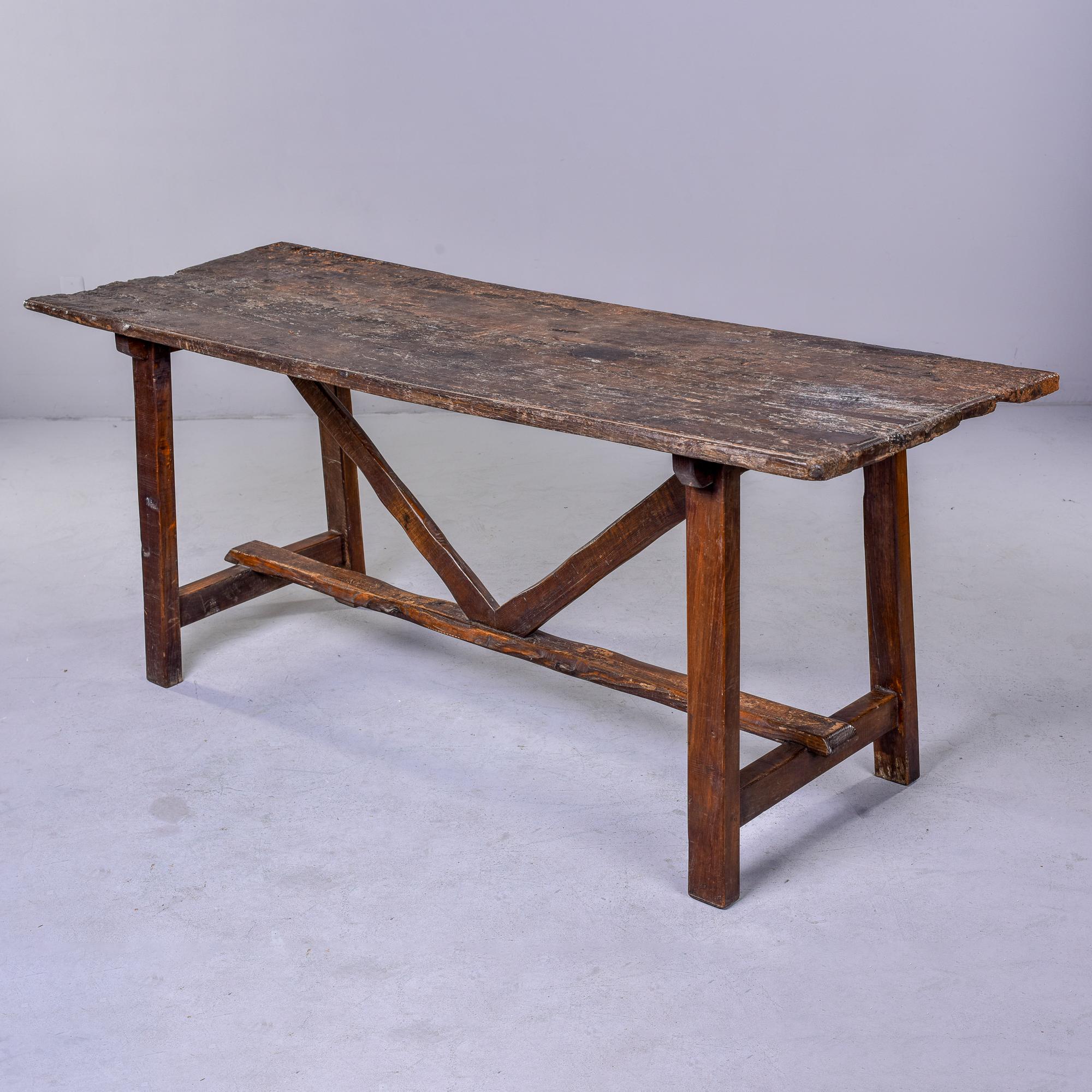 Circa 1840s dark oak trestle table found in Italy. Simple, primitive styling with four legs, a center stretcher and V-form supports. Wood surfaces show a lot of honest wear, patina and texture. See detail photos. Table is structurally sound.
