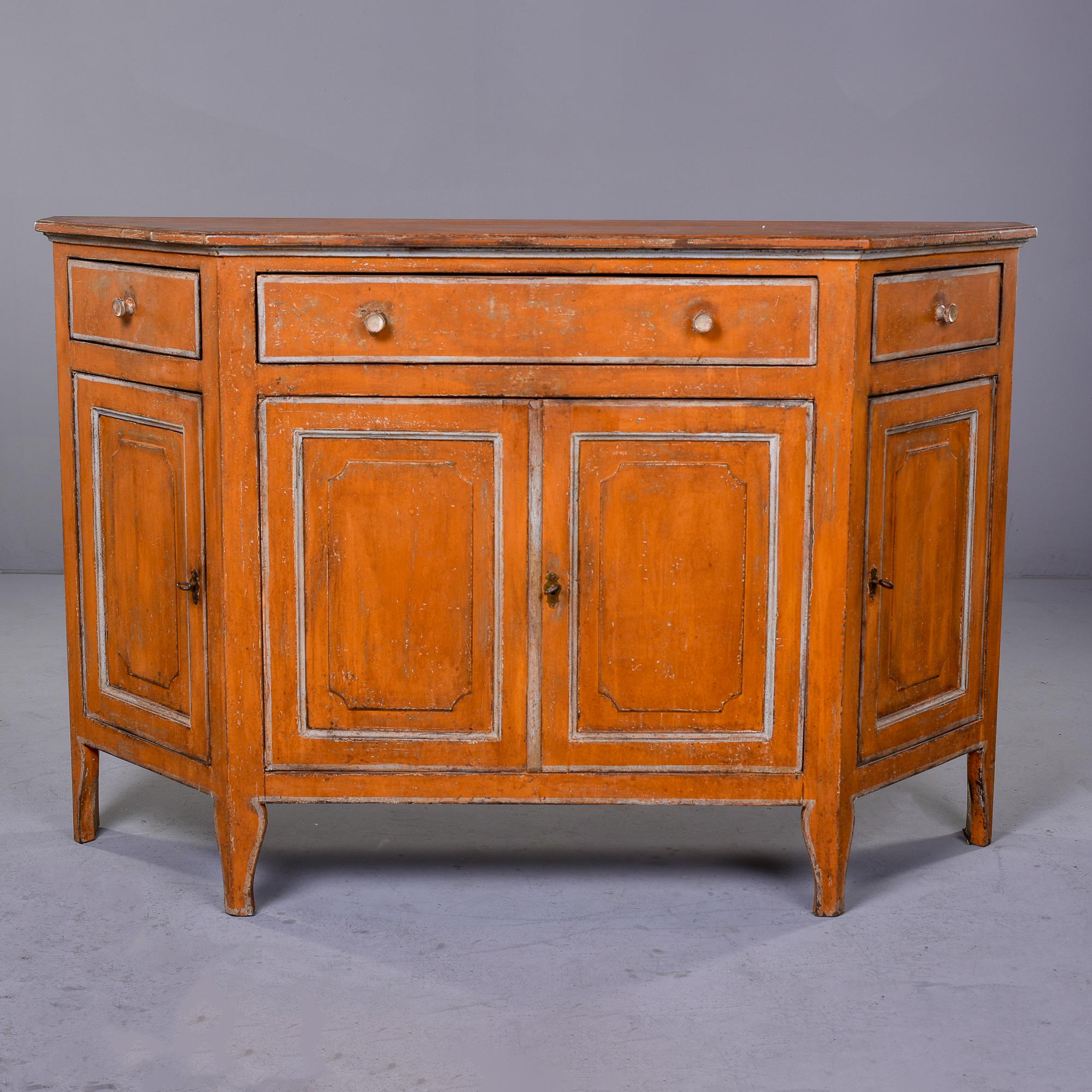 Circa 1890s painted buffet from the Bologna region of Italy. Cabinet is painted a muted pumpkin color with contrasting milky white trim. Center section has narrow drawer over a locking storage cabinet with two hinged doors and a fixed internal