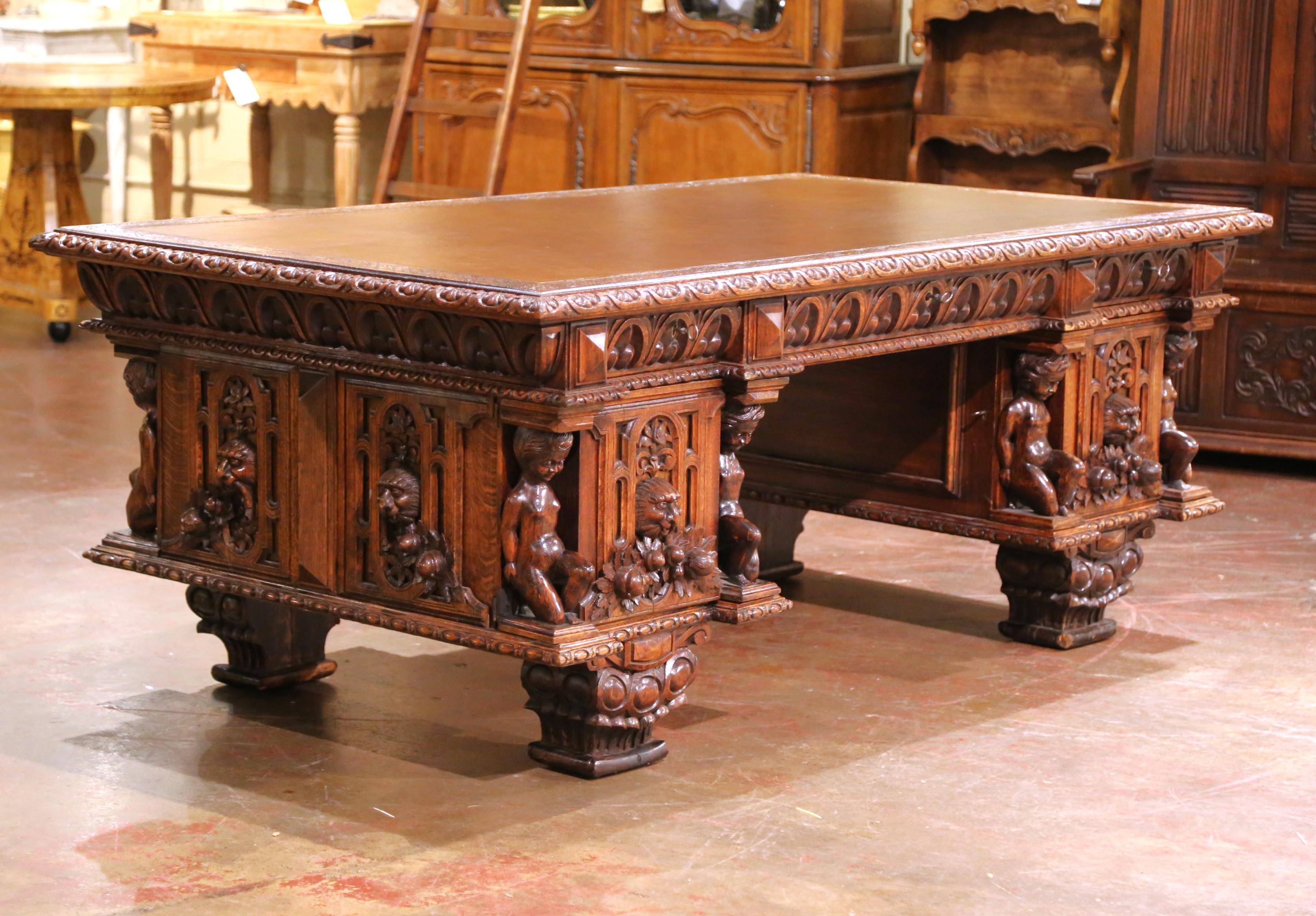 Crafted in Italy circa 1870, this impressive 19th century carved oak partner desk is a striking example of Renaissance Revival artistry, designed to be finished and admired on all sides. The large rectangular surface features a rich brown tooled