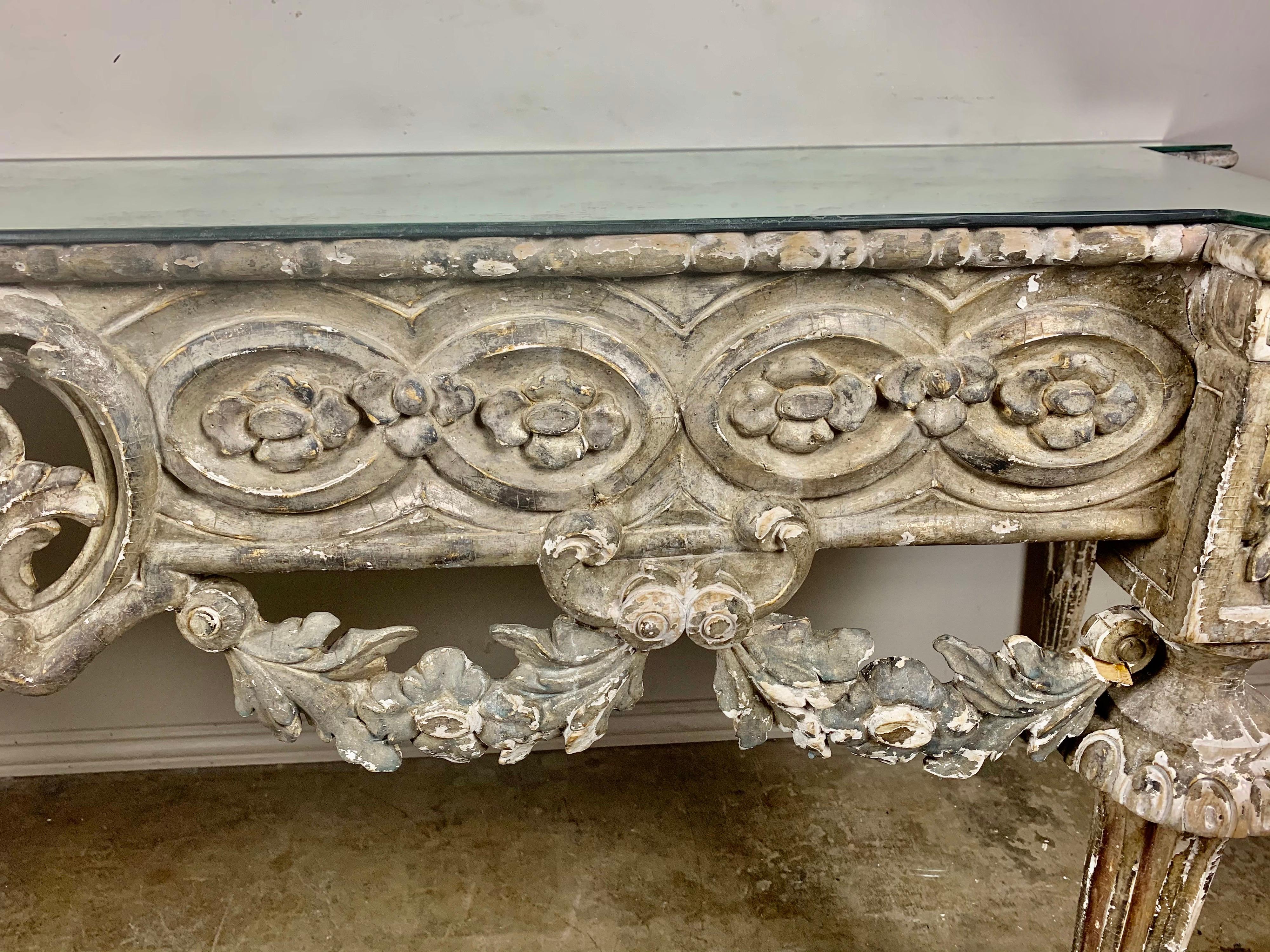 19th century Italian Rococo style console. The table stands on four fluted tapered legs. The front apron is decorated with carved garlands hanging from a carved panel with a center cartouche. There is intricate carving and details throughout. The