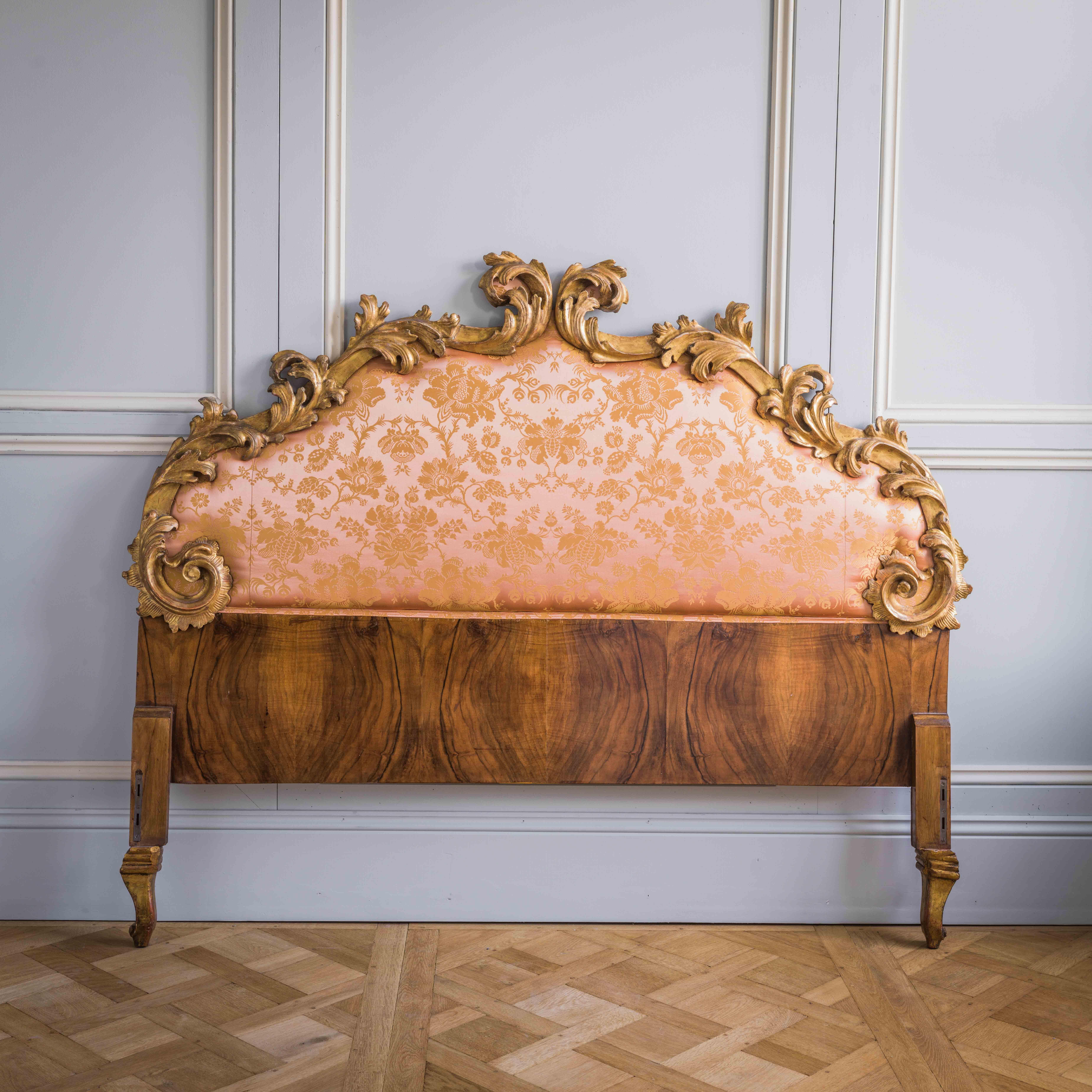 A late 19th century, Italian, Rococo style headboard featuring deeply scrolled, hand carved, acanthus leaves which reflect the warmth and brightness of their original water gilding with the addition of an overall naturally time aged patina. The
