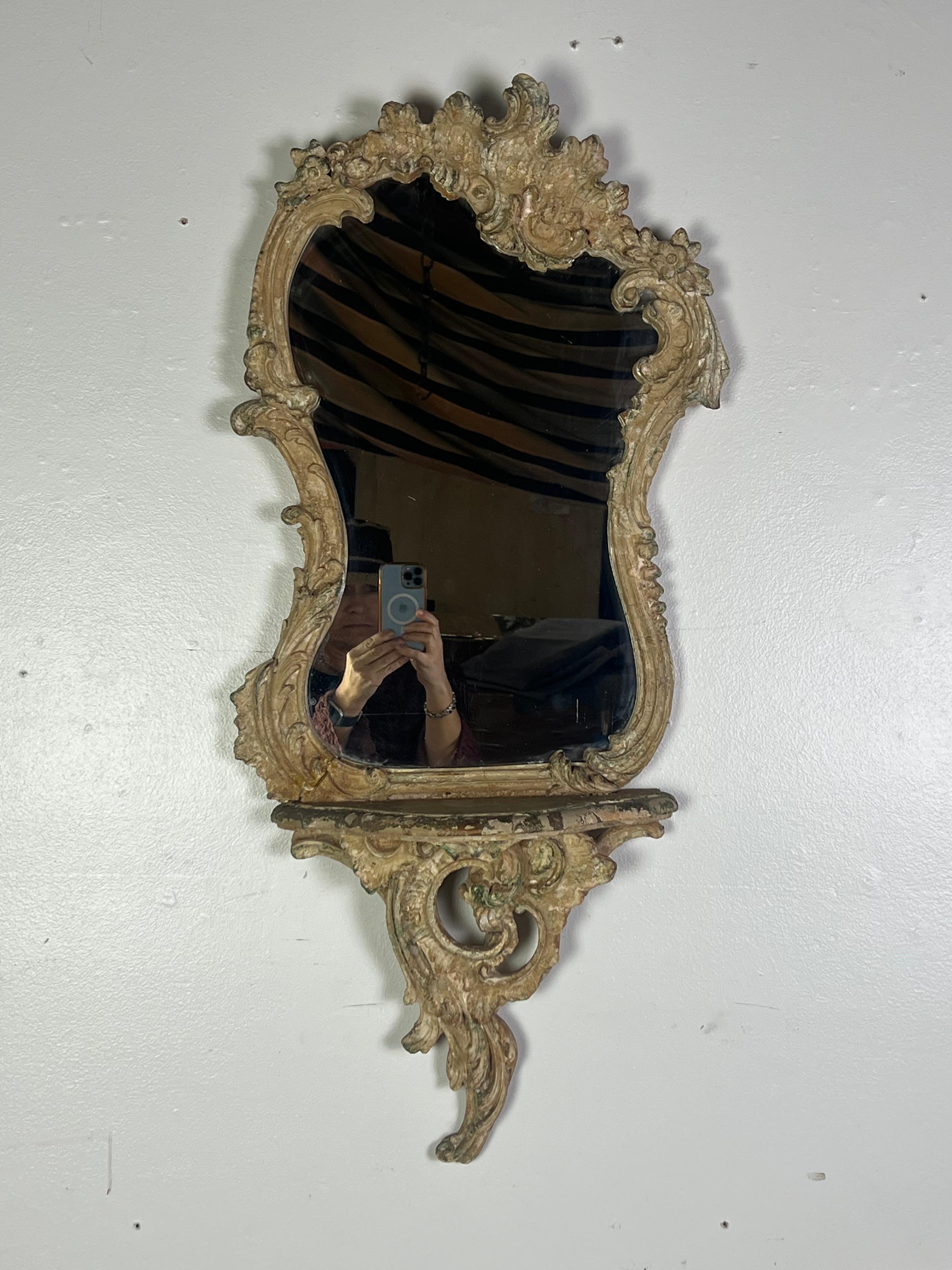 19th century Italian Rococo style carved gilt wood mirror with an accompanying shelf, featuring the intricate carvings of scrolled acanthus leaves and flowers.