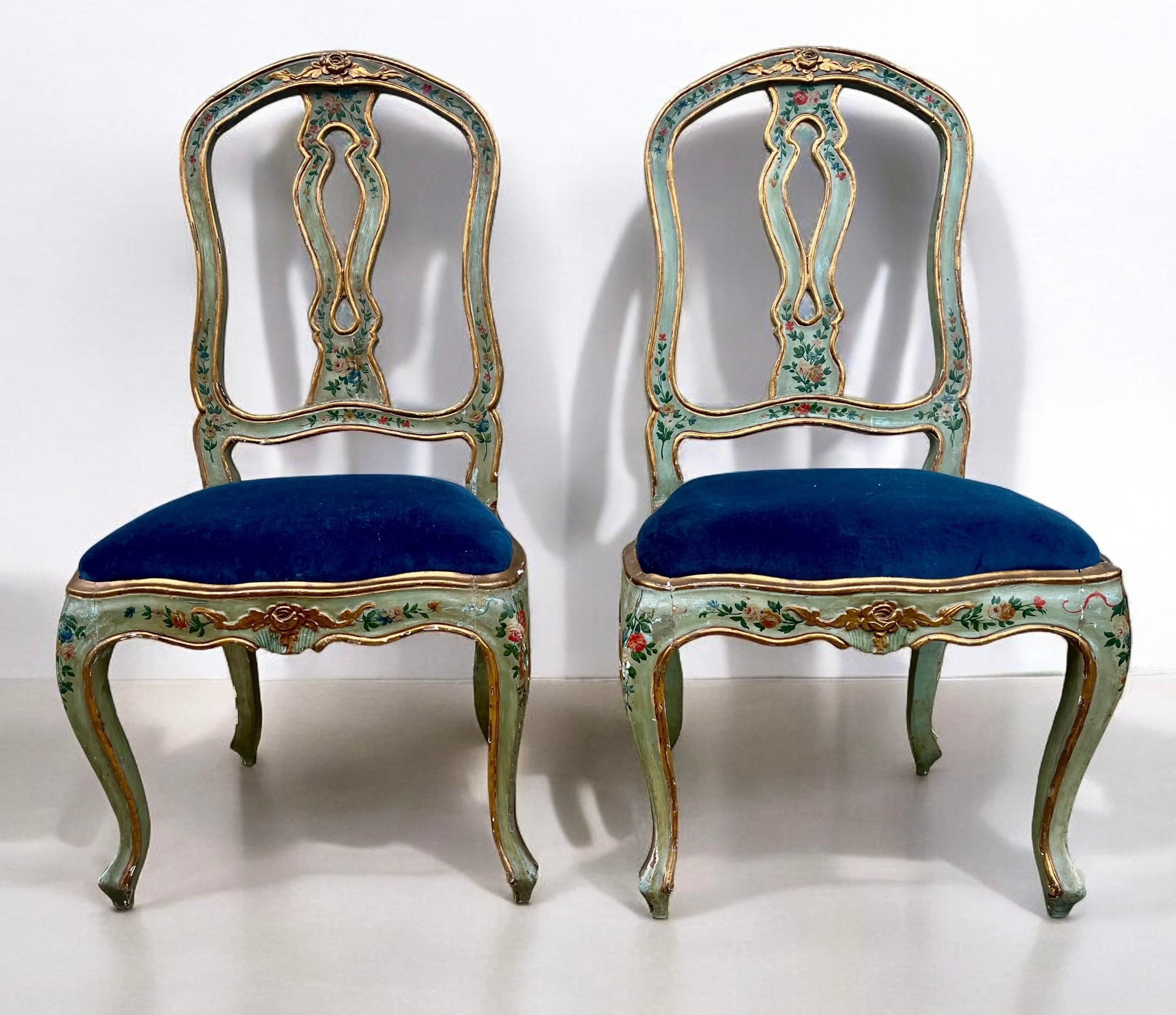 This is a pair of 19th century hand painted Venetian side chairs. The seats are in a blue velvet that is in very good condition. The frames are a celadon color with flowers and gilt trim. They have a general wear typical of antique Venetian