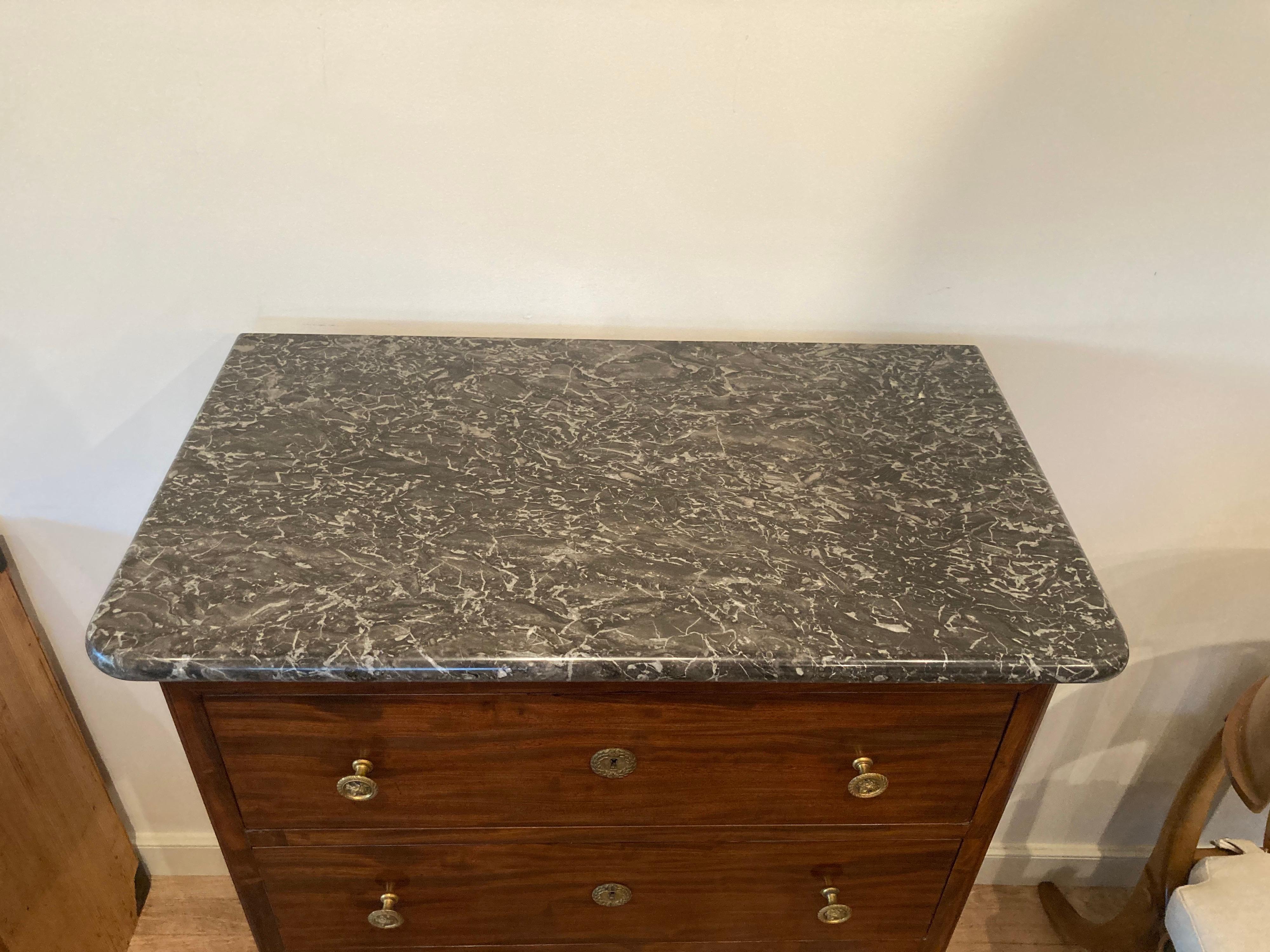 19th century French marble top chest, stamp signed ''Jacob'' below marble, with rounded front corners and four drawers having brass pulls with face relief, set on carved paw feet.