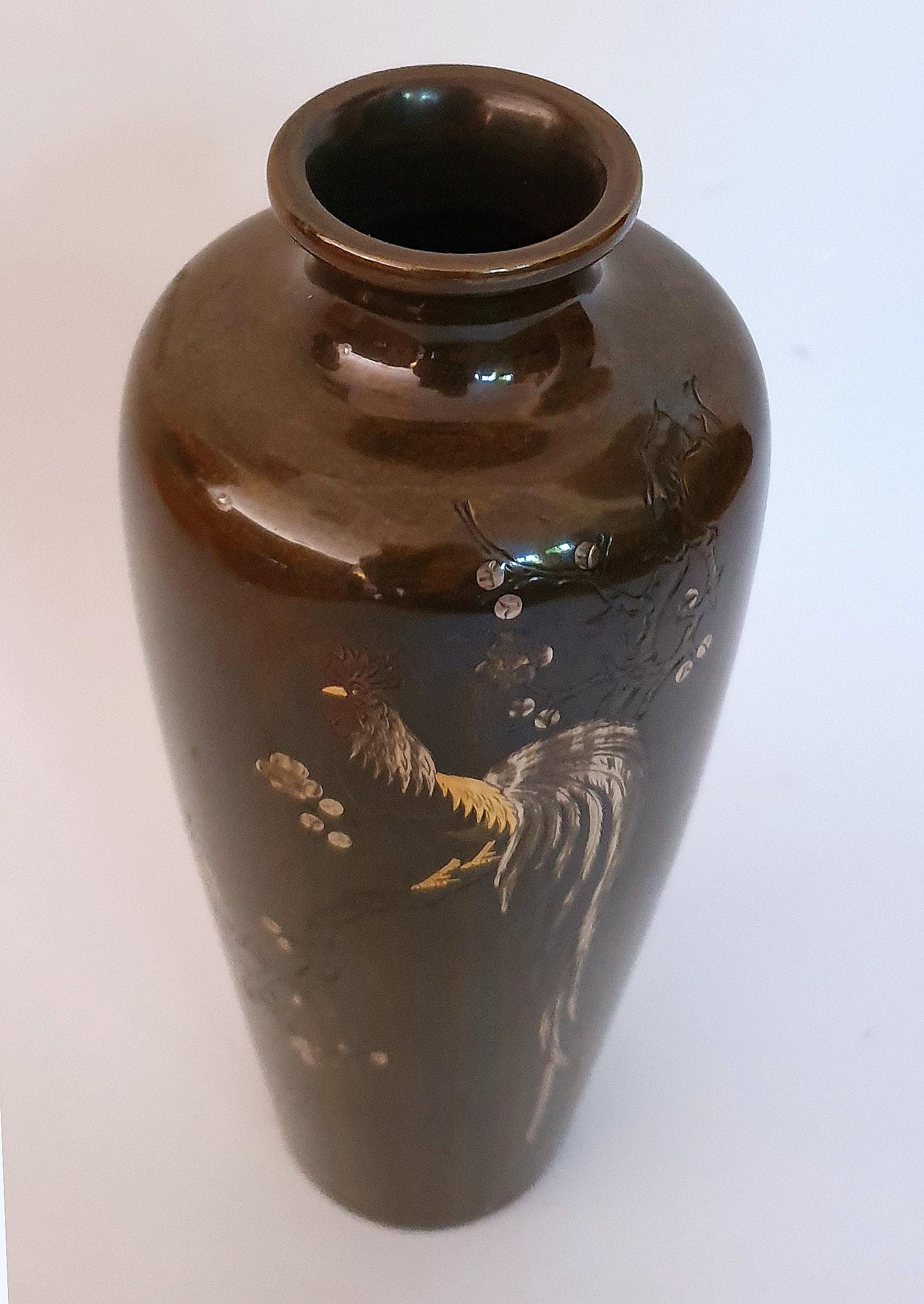 A 19th century Japanese Meiji period marinated bronze vase inlaid with gold and silver depicting an exotic bird perched on a blossoming branch. The vase is signed to the side of the vase and to the underneath. It measures 7 in – 17.8 cm high, 3 in –