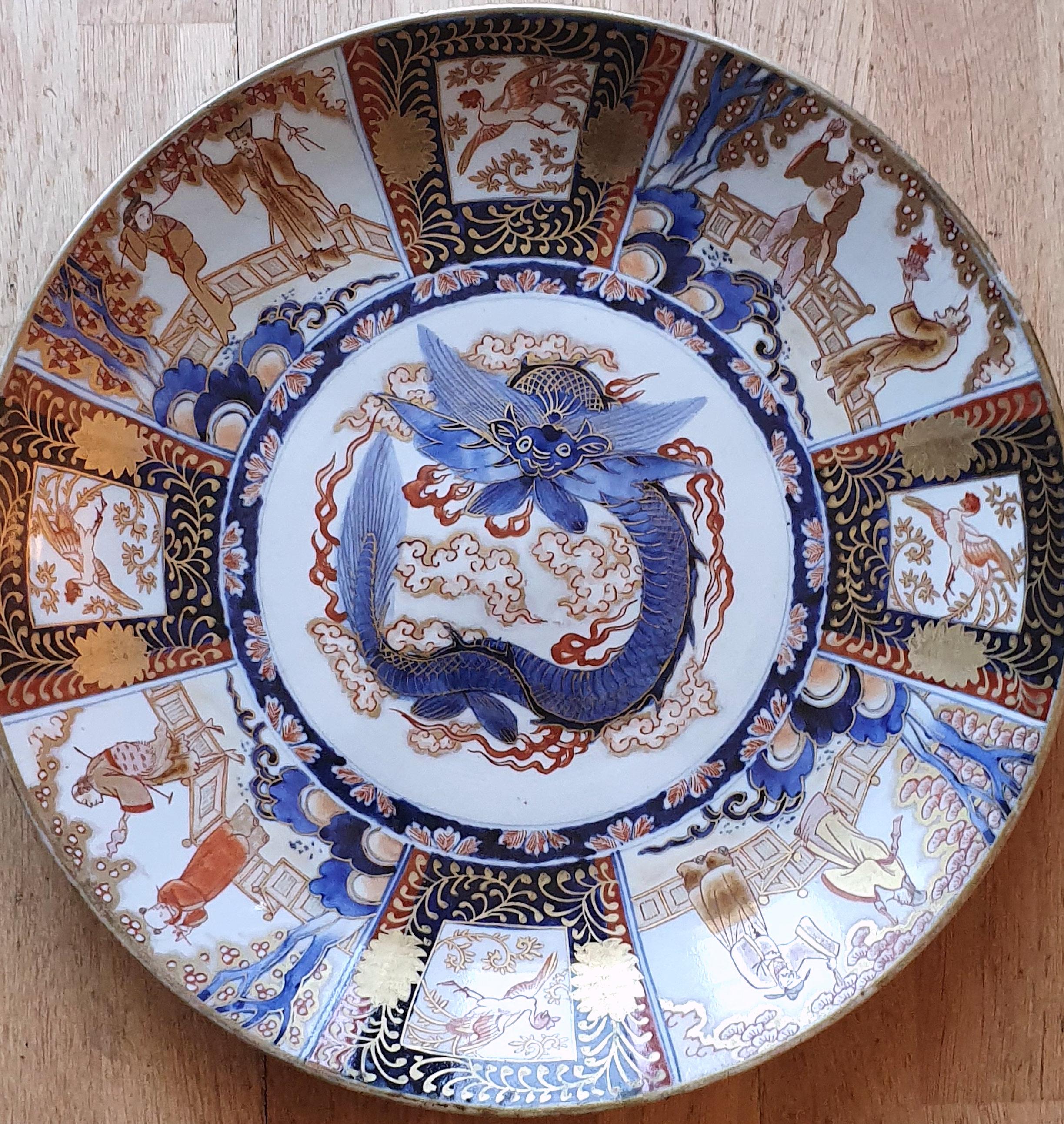 This 19th century Japanese Meiji period pottery Imari charger, painted with a central dragon flanked by panels depicting figures and exotic birds with gilded highlights. The plate measures 15 ¾ in - 40 cm in diameter and 2 in – 5 cm in height. This