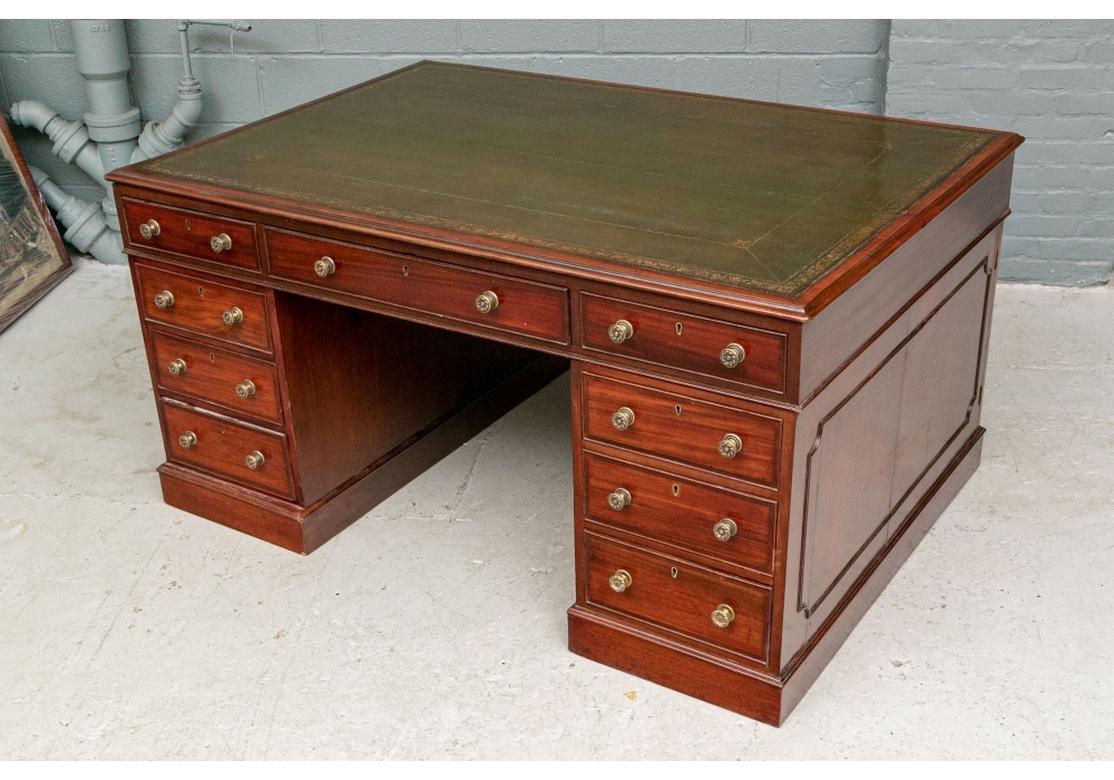 A fine mahogany knee hole desk, the top with carved edge and inset olive green embossed leather writing surface. The front with three frieze drawers over three short drawers on each side with fine brass knob pulls with a swirled pattern. The back