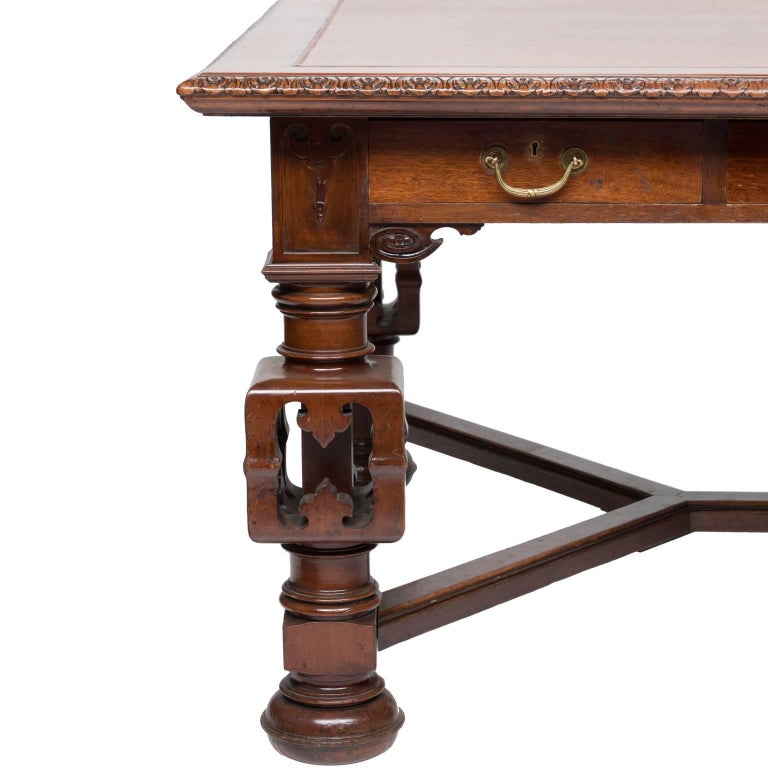 A very large and impressive English writing desk/game table from the late 19th century. Gadrooned edging, leather inserted top with blind tooling, three drawers on two sides, well-carved apron, turned legs with a bulbous style mid-section fretwork
