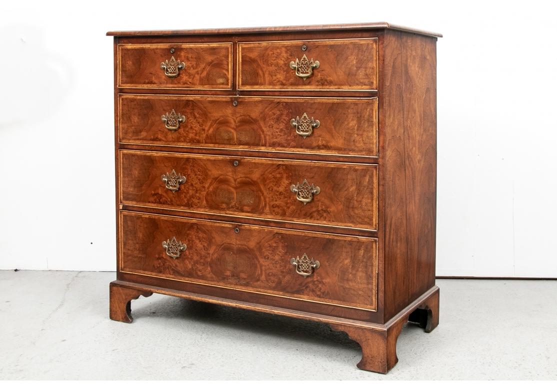 The top made of book matched figured wood with cross banding and fine herringbone string inlay. With a bull nose edge. The tall chest with two short over three long drawers with book matched fronts and matching herringbone string inlays, and fine