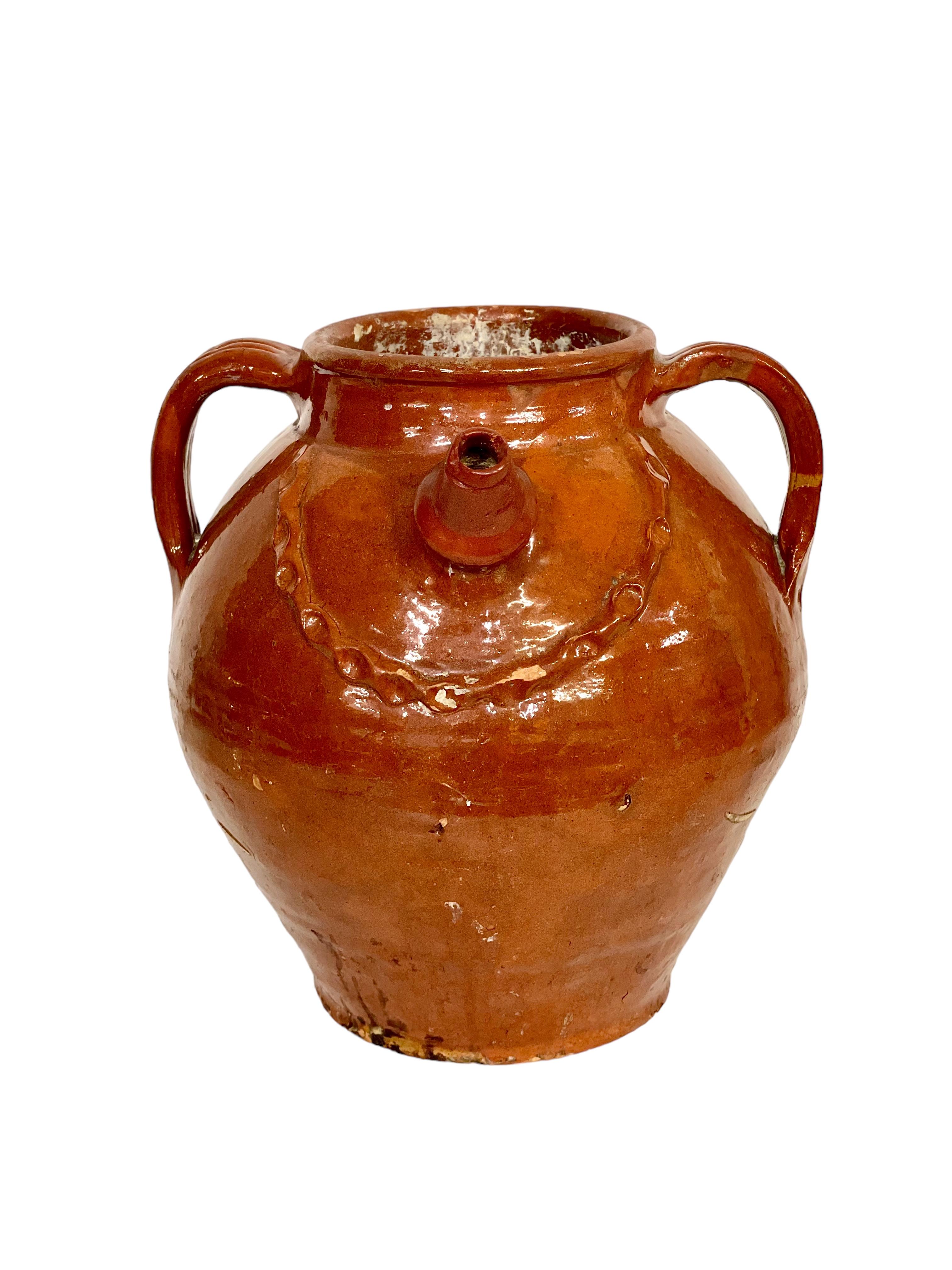 A charming and capacious 19th century walnut oil jug originating from the Dordogne region of south-west France, and decorated with a gorgeously glossy nut-brown glaze. Three shaped and grooved side handles encircle the wide rim, with a handcrafted