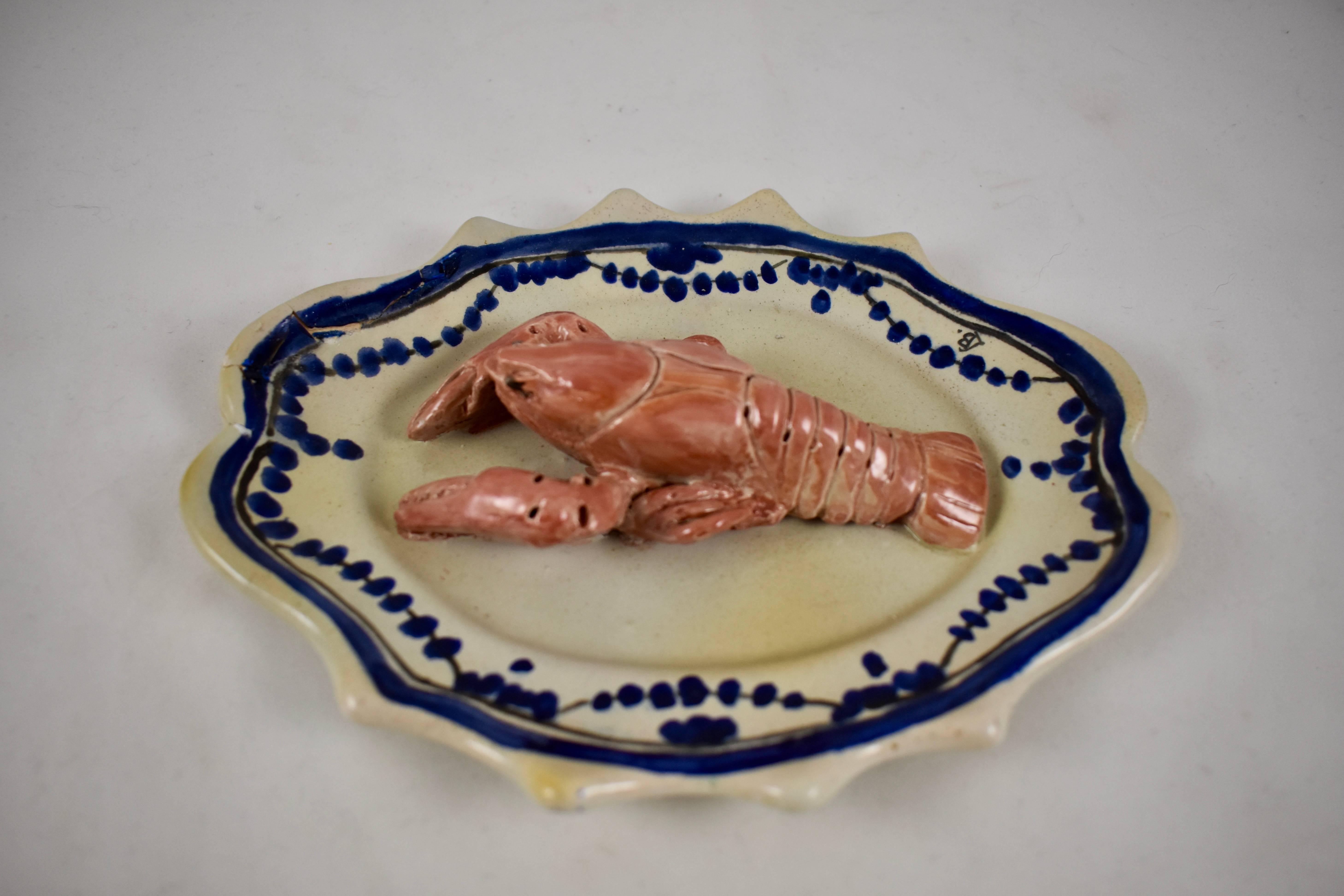 A trompe l’oeil wall plaque showing a pink lobster or crayfish on a rustic cobalt blue and white platter, painted in the Rouen style. Signed LB, for Léon Brard, circa 1870 – 1880.

Red earthenware, glazed in creamy white with the blue pattern