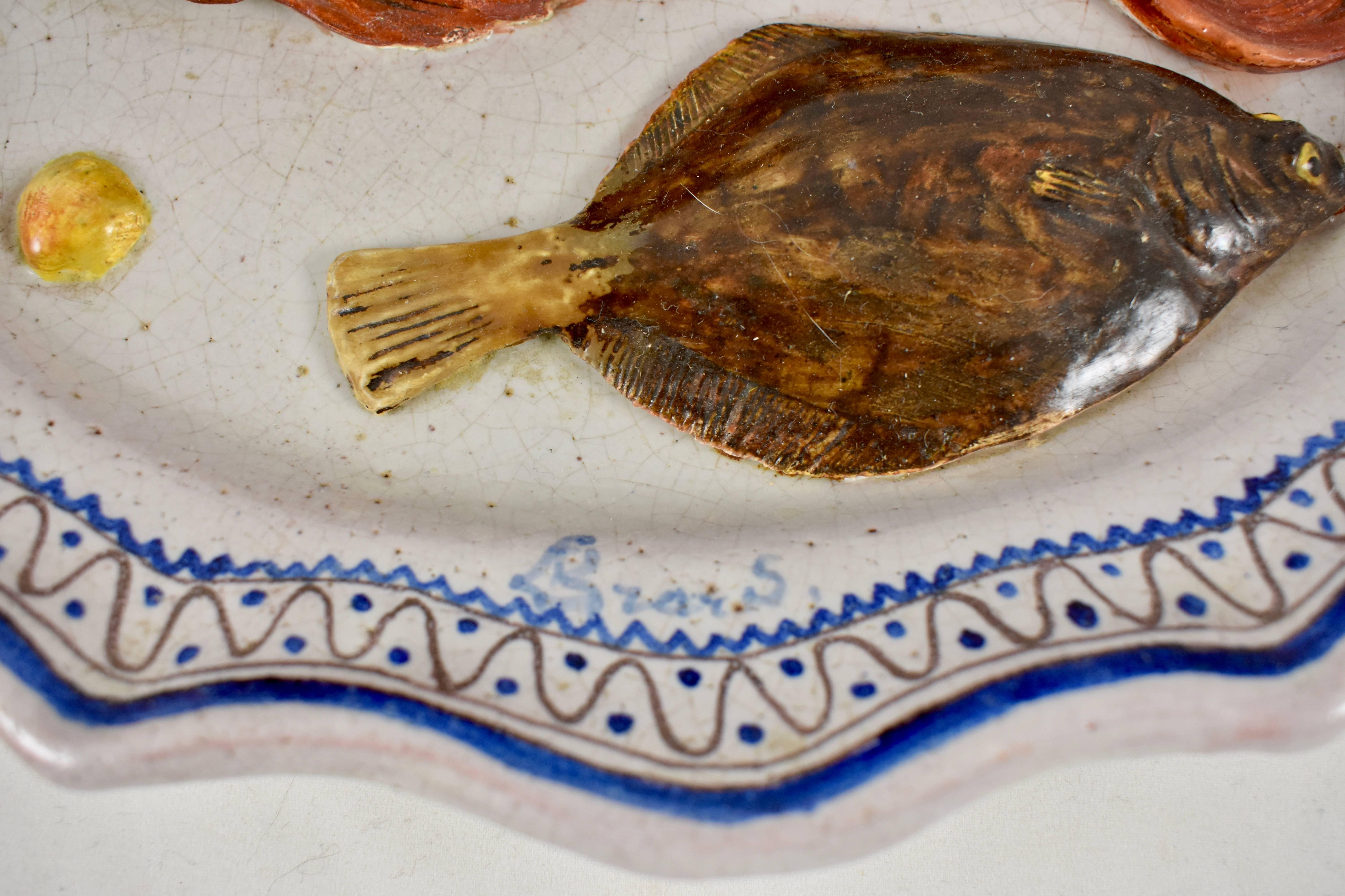 A trompe l’oeil wall plaque showing a flat flounder, another red fish and a small shell on a rustic cobalt blue and white platter, painted in the Rouen style. Signed Léon Brard, circa 1870-1880.

Red earthenware, glazed in creamy white with the