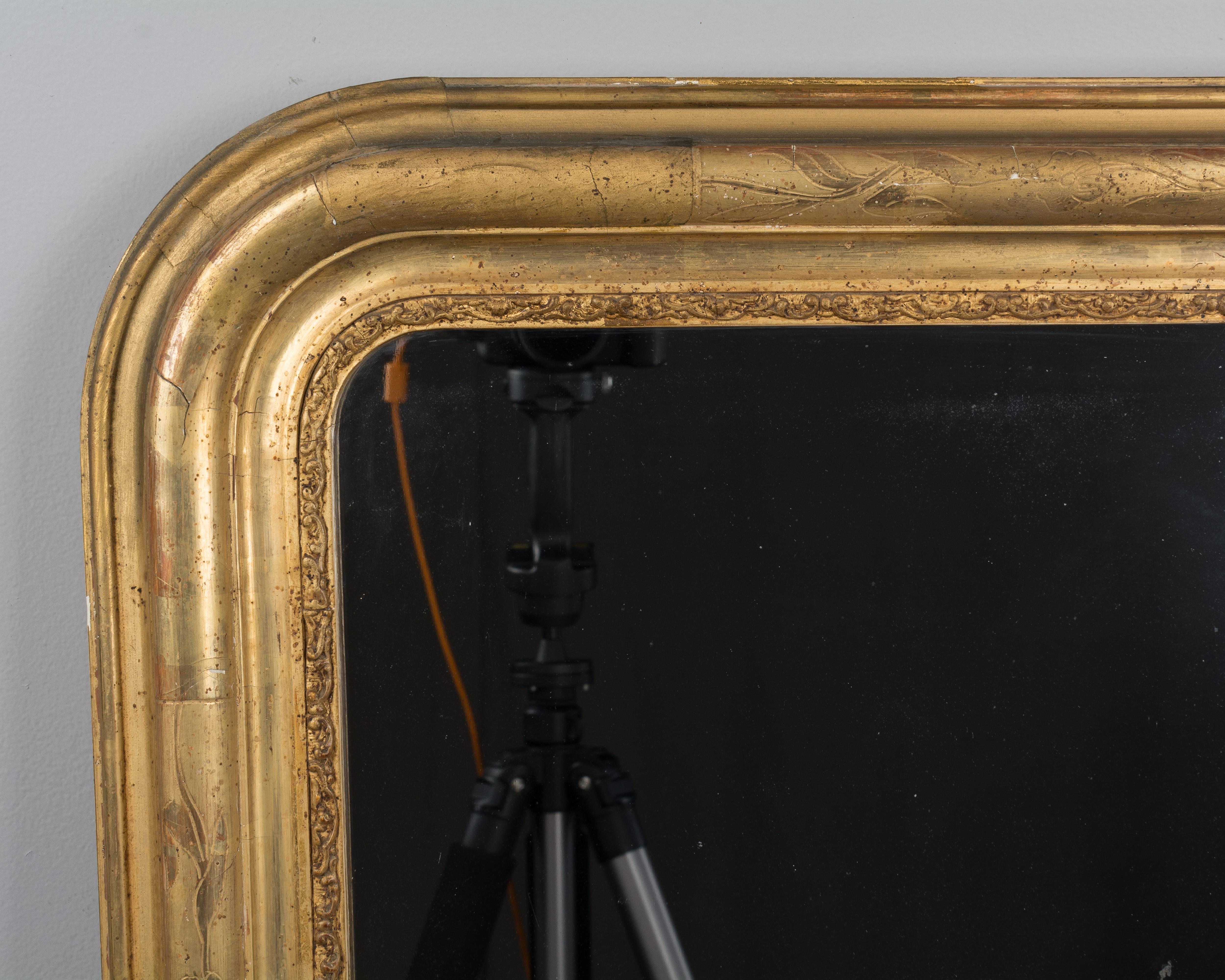 A 19th century Louis Philippe gilded mirror with curved top corners, bright gilt with incised decoration. Original mirror with old silvering. Dimensions are 26.25