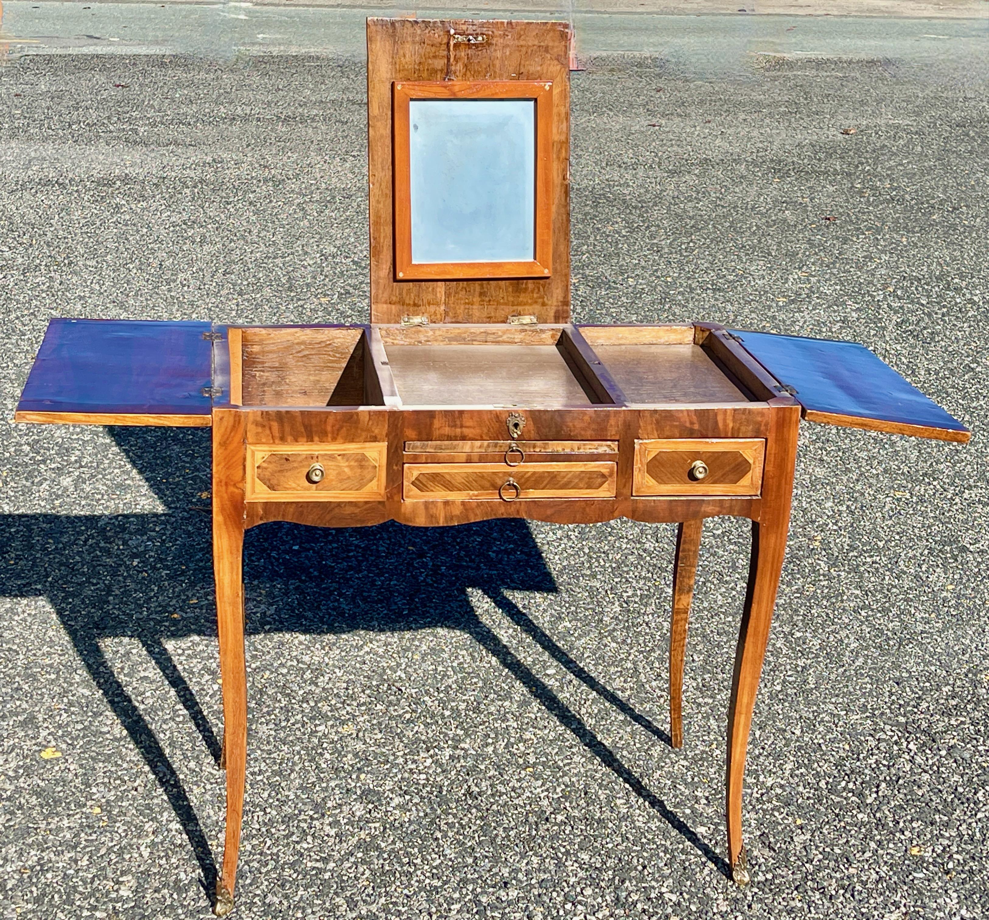 French nineteenth century Louis XV vanity dressing table, poudreuse or coiffeuse standing on four slender tapering cabriole legs. The top is divided into three parquetry framed panels decorated with elaborate mirrored parquetry; the central top