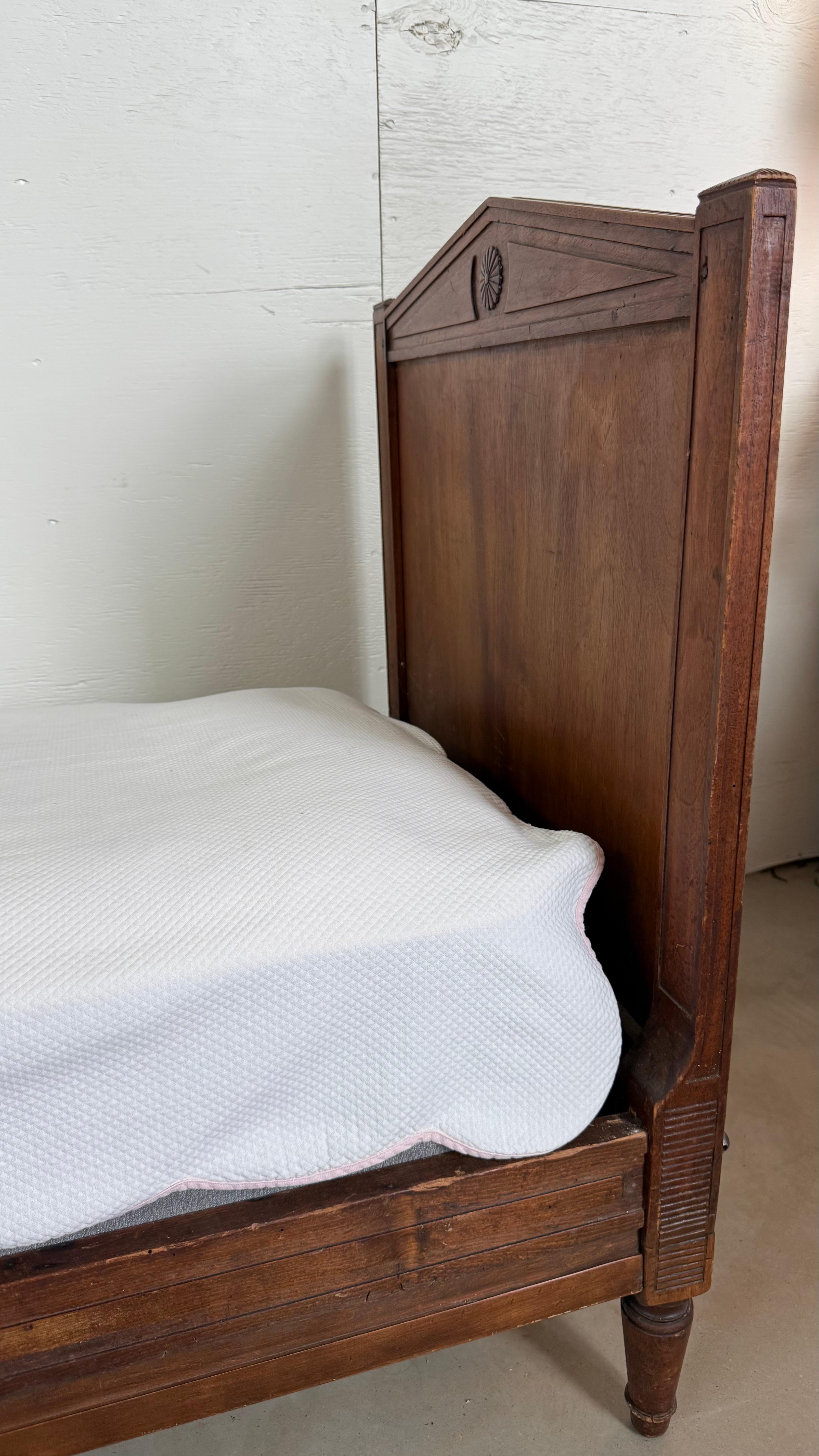 A graceful 19th-century Louis XVI style daybed, embodying the refined neoclassical elegance of the era. Crafted with a carved wood frame and finished in a soft, timeworn patina, this piece features signature Louis XVI details—including fluted legs,