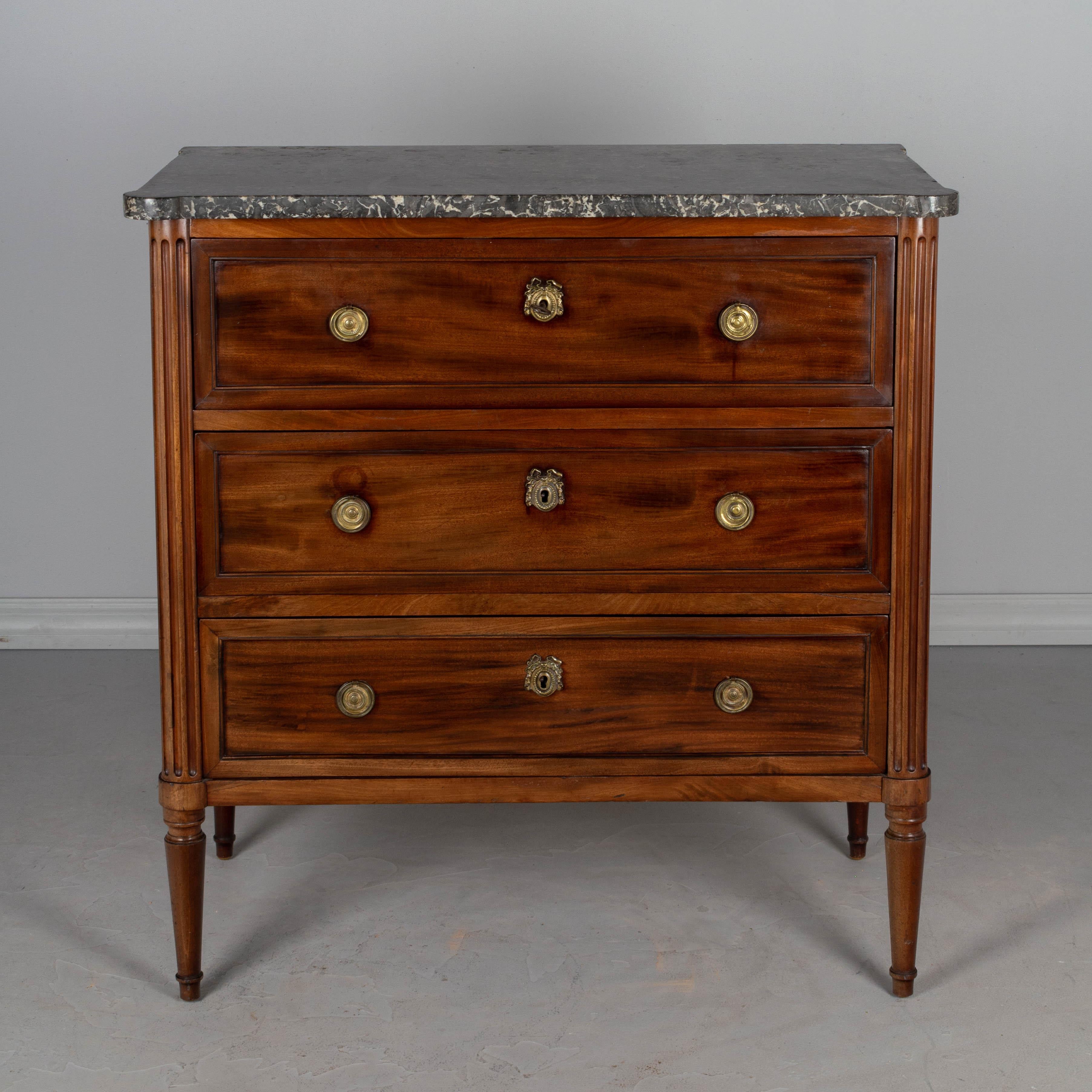 A 19th century Louis XVI style French commode, or bachelors chest, with two dovetailed drawers and a top drawer that pulls out to reveal a desk. Interior has a dark green leather writing surface and two dovetailed drawers above two false drawers.