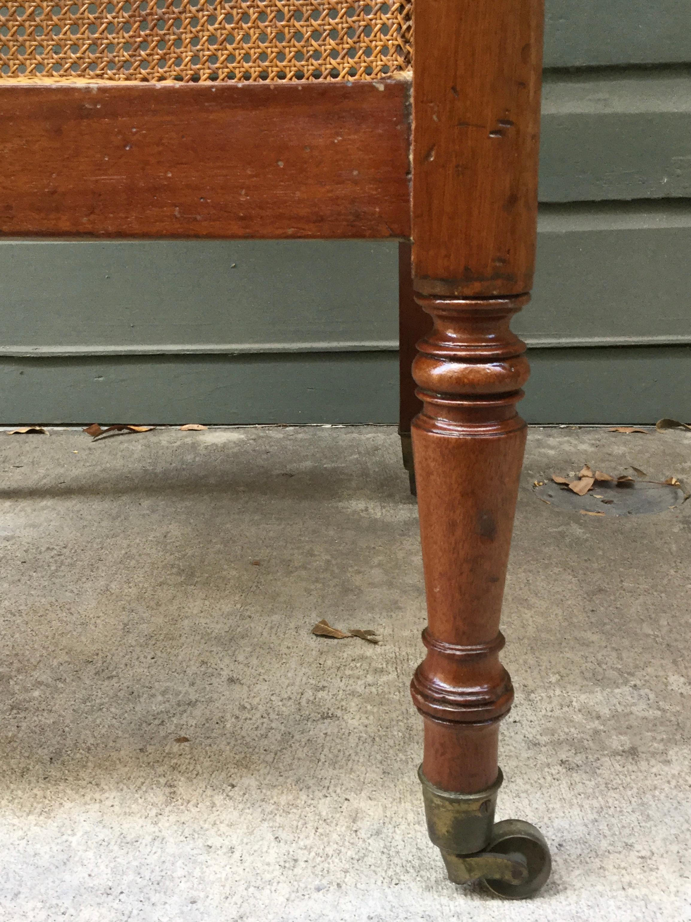 Classic Regency hand caned mahogany library chair / bergère. This library chair is made out of solid mahogany framing the caning. The armrest terminate into a reeded hand rest that are sitting above solid mahogany turnings for the Classic legs