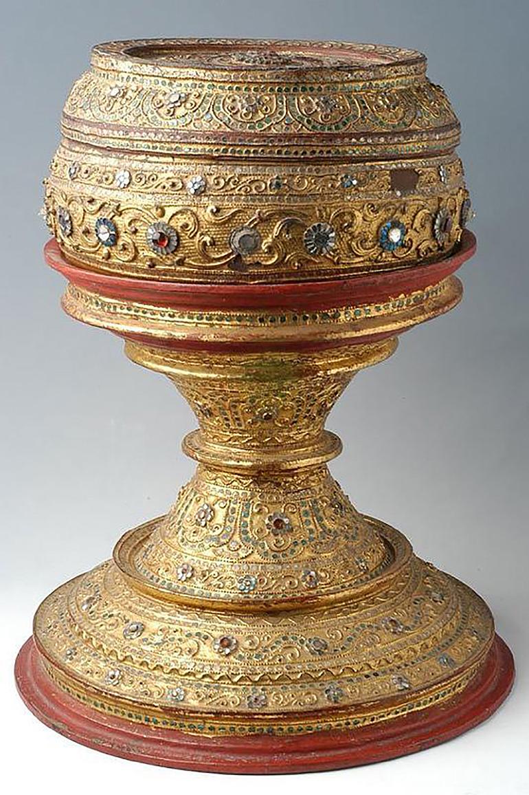 Beautiful Burmese offering bowl coated with lacquer and decorated with mirror tiles.
The body was made of bronze and the cover and base were made of wood.

Age: Burma, Mandalay Period, 19th Century
Size: Height 48 C.M. / Width 38