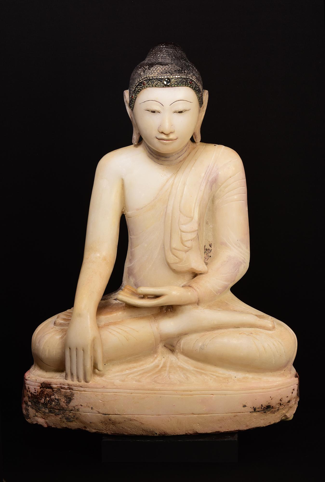 Grand bouddha ancien en albâtre de Birmanie, assis en posture de Mara Vijaya (appelant la terre à témoigner) sur une base, avec incrustation de morceaux de verre colorés sur le bandeau.

Âge : Birmanie, période Mandalay, 19e siècle
Dimensions :