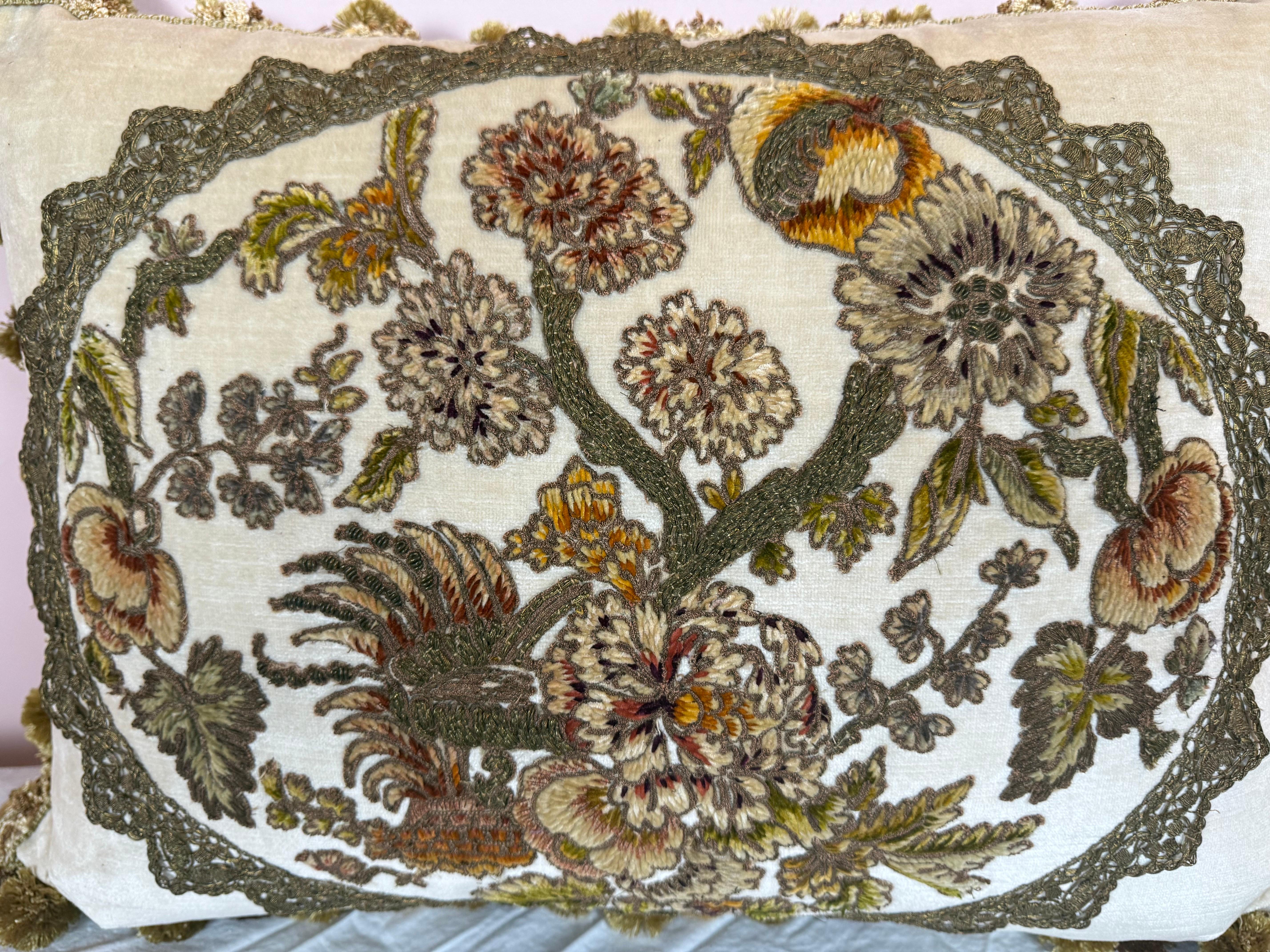 Questo elegante cuscino presenta un lussuoso inserto in piuma d'oca racchiuso in una fodera di velluto color crema. Il pannello anteriore presenta uno squisito ricamo francese del XIX secolo in ciniglia e metallo, che raffigura un elaborato motivo