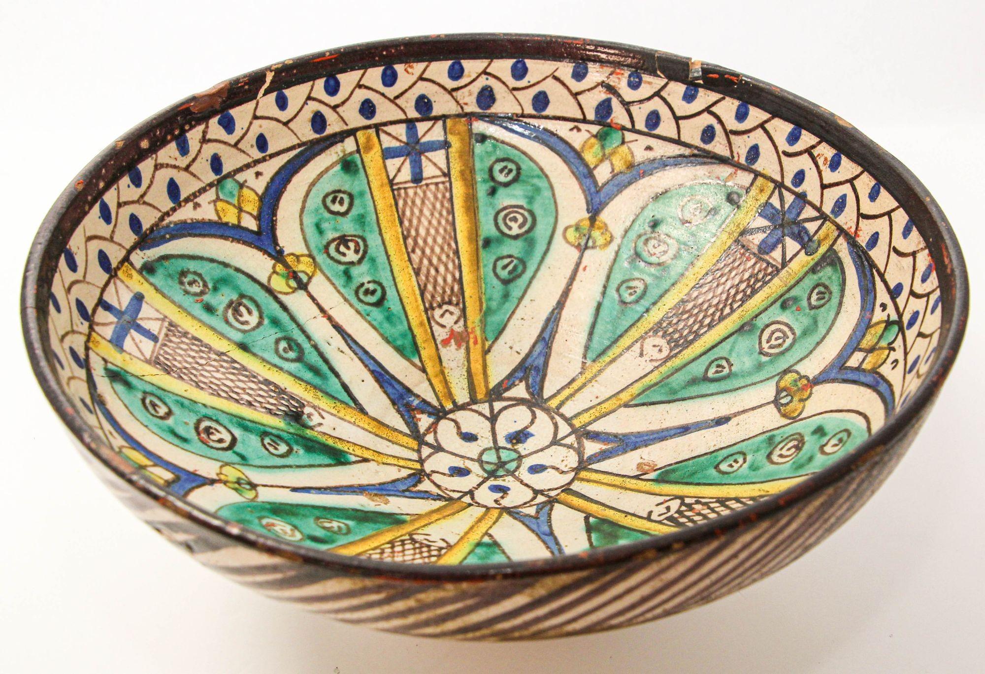 Antique 19th C. Moroccan Ceramic Bowl Polychrome Footed Dish Fez.
A 19th-century antique ceramic footed bowl from Morocco, Fez, showcases the exquisite artistry of Mokhfia polychrome pottery.
The bowl boasts a deep rounded form with a flattened rim,