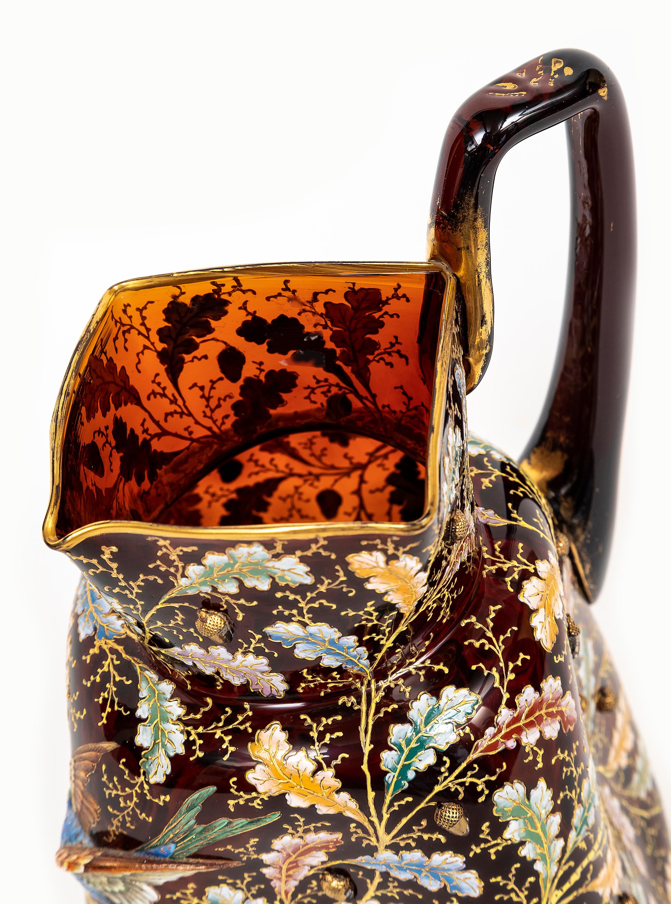 An Incredible 19th Century Moser Ruby Red Crystal Enameled Gilt Pitcher with Applied Enamel Parrot and Enameled and Gilt Surface Leaves.  Of pinched quatrefoil form, in translucent amberline or ruby red crystal, decorated with trailing oak-boughs