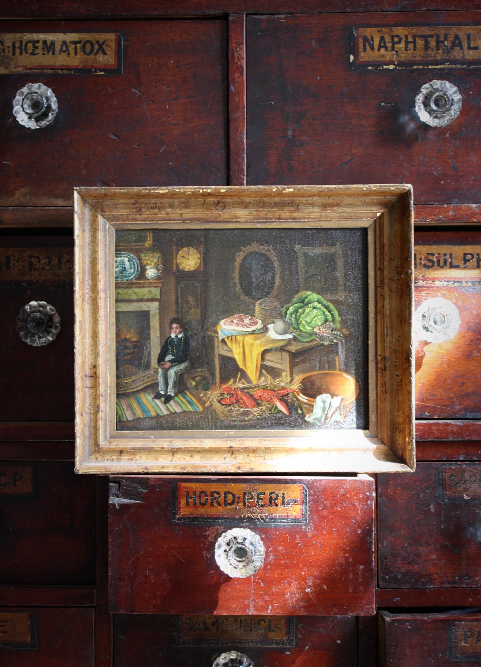 A intriguing early 19th century naive oil on board, showing a well furnished interior scene of a wee lad with a table ladened with oversized food. 

circa 1810

A label on the reverse showing the Rutland Gallery London, provenance from the