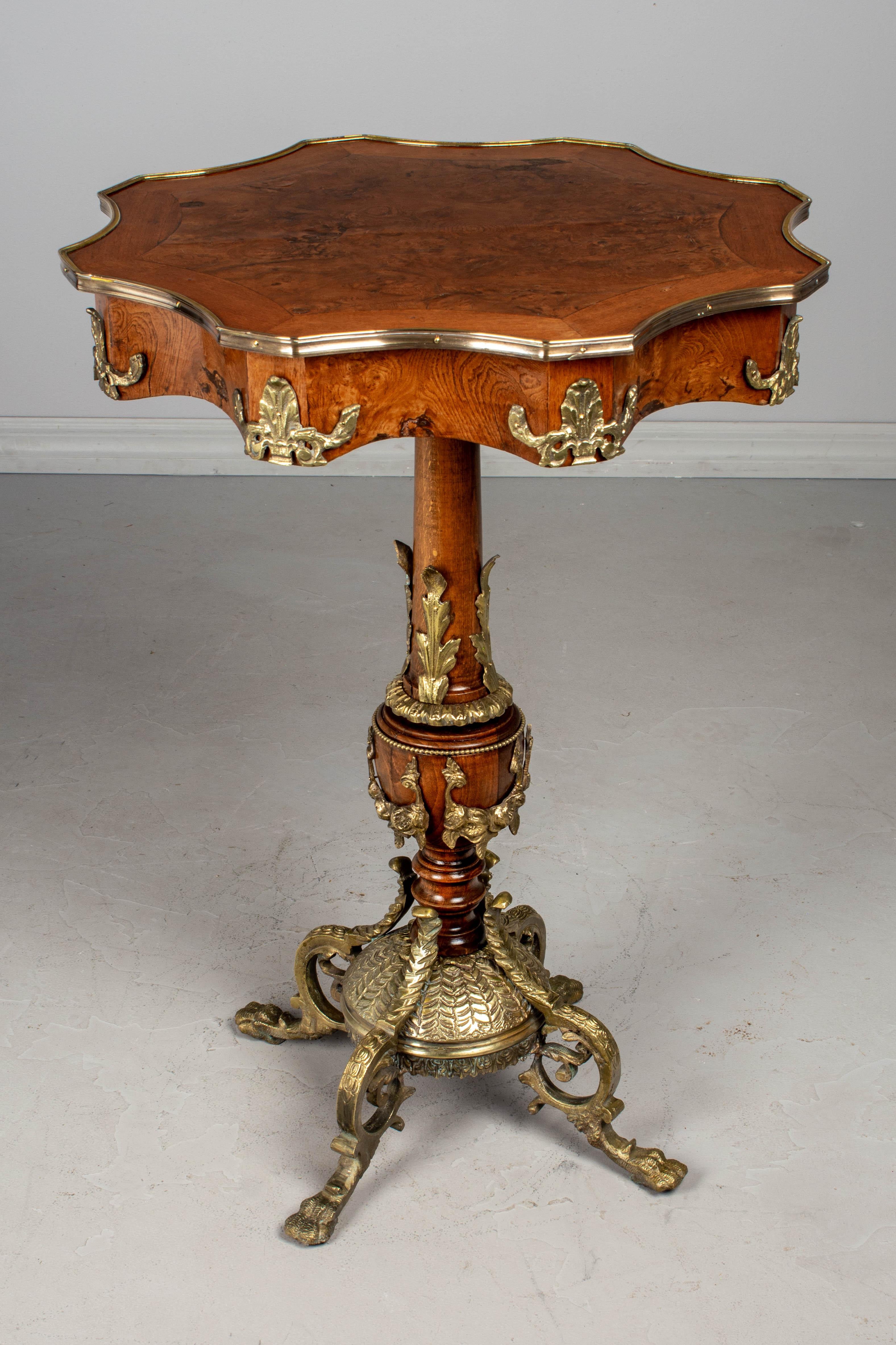 An exquisite 19th century French Napoleon III bronze mounted guéridon. This tall pedestal table has a shaped top made of veneer of walnut and beautifully patterned veneer of burled elm with bronze surround. French polish finish. The central turned