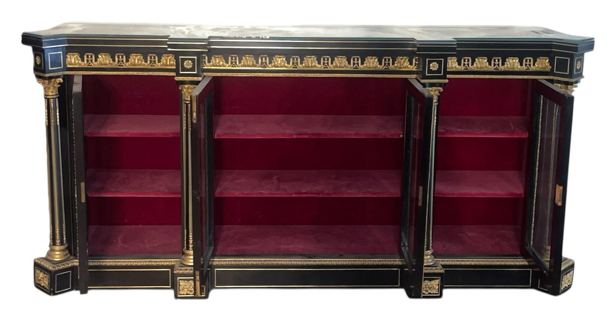 Una magnifica vetrina francese Boulle del XIX secolo, di dimensioni impressionanti e di raffinata fattura, riccamente decorata con intarsi in ottone e tartaruga secondo la tradizione Boulle. Il mobile presenta pannelli ebanizzati incorniciati da