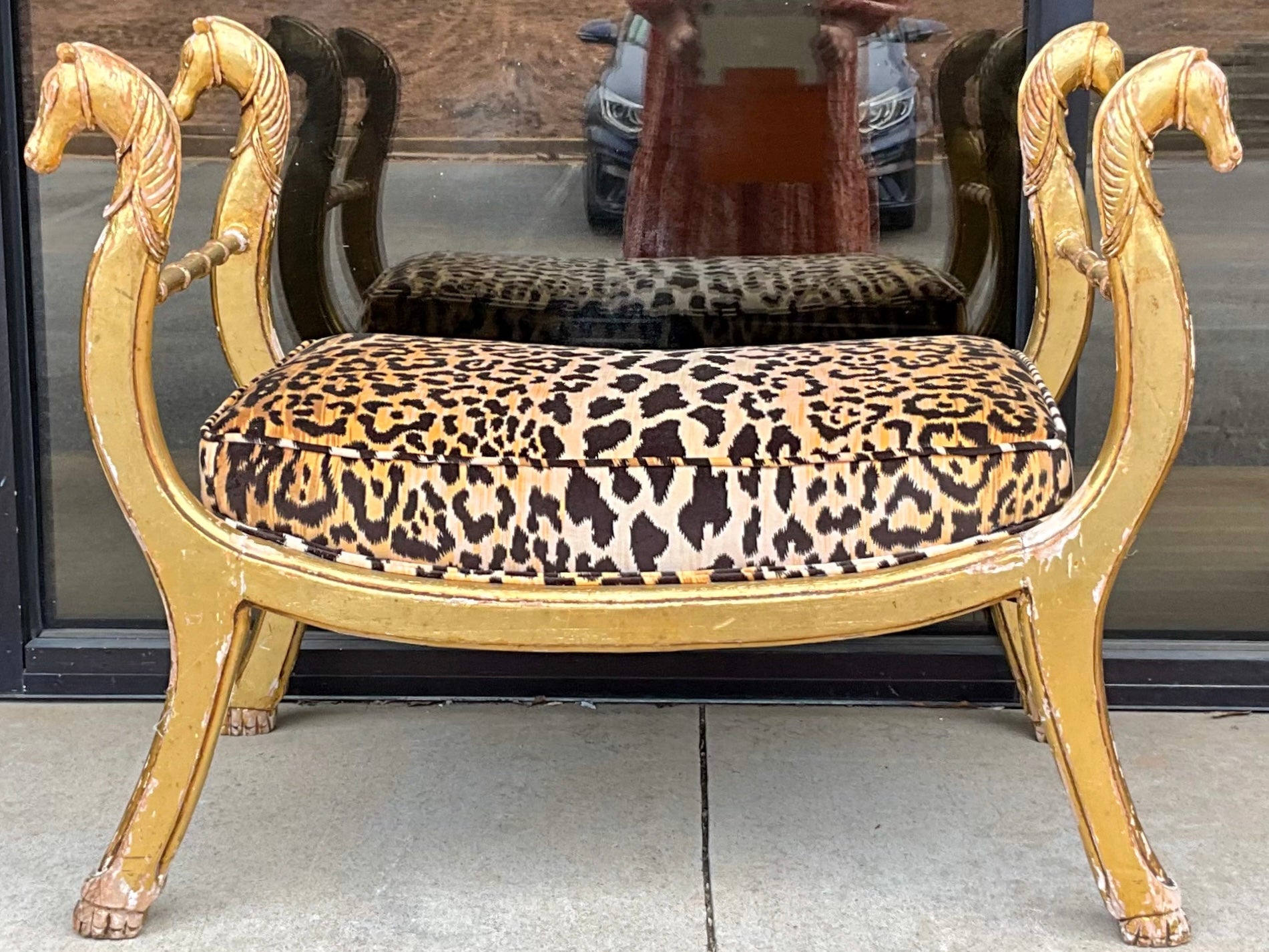 This is an antique neo-classical style Italian carved giltwood bench in the manner of Maison Jansen. The leopard velvet is new. There is chippiness to the gold leaf frame. Each arm is a carved horse. I have a second if interested in a near pair.