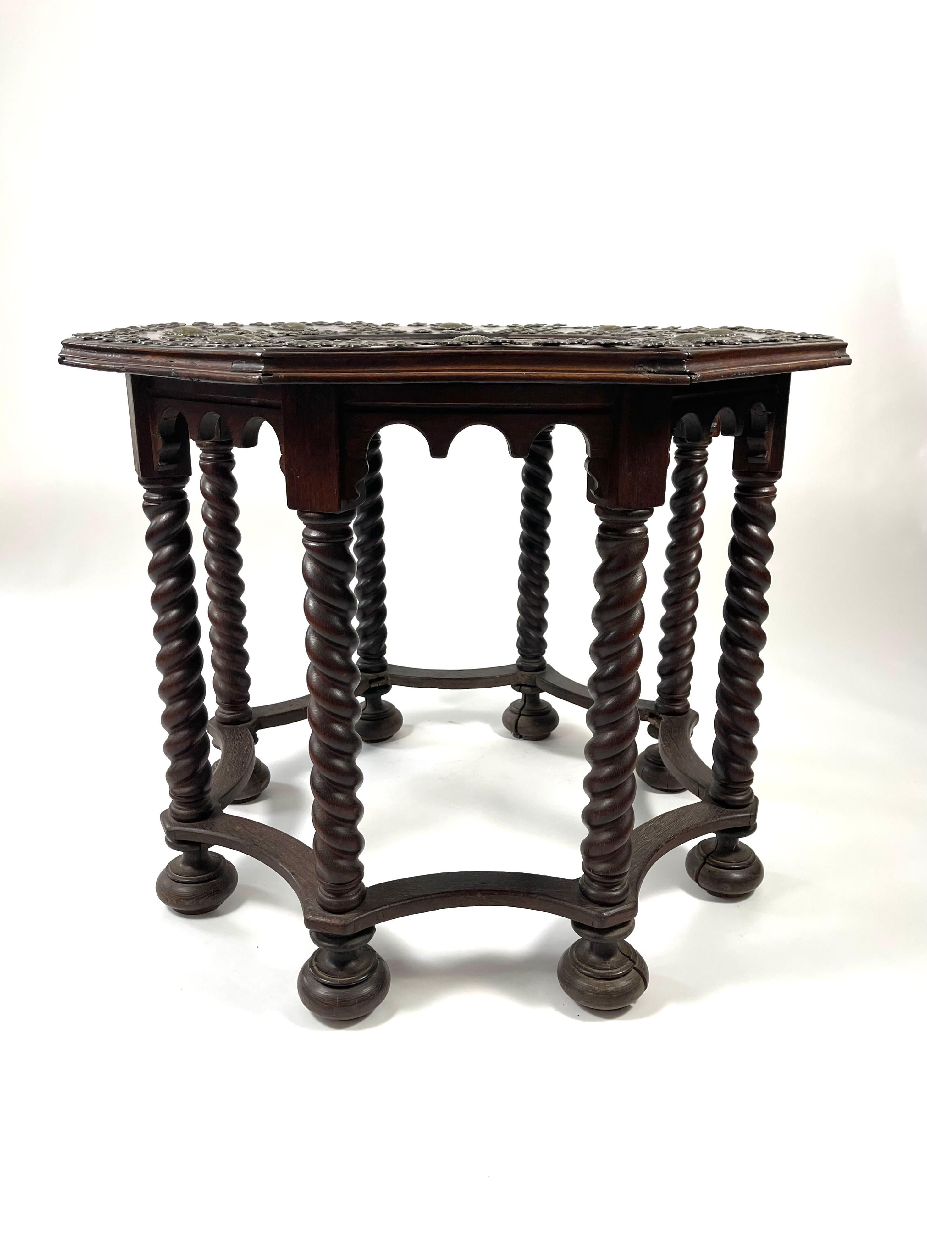 A late 19th century Italian or Spanish carved oak octagonal center table, the top with beautifully inlaid specimen marble top decorated with cast brass scallop shells and flower head, supported by barley twist legs, raised on bun feet.