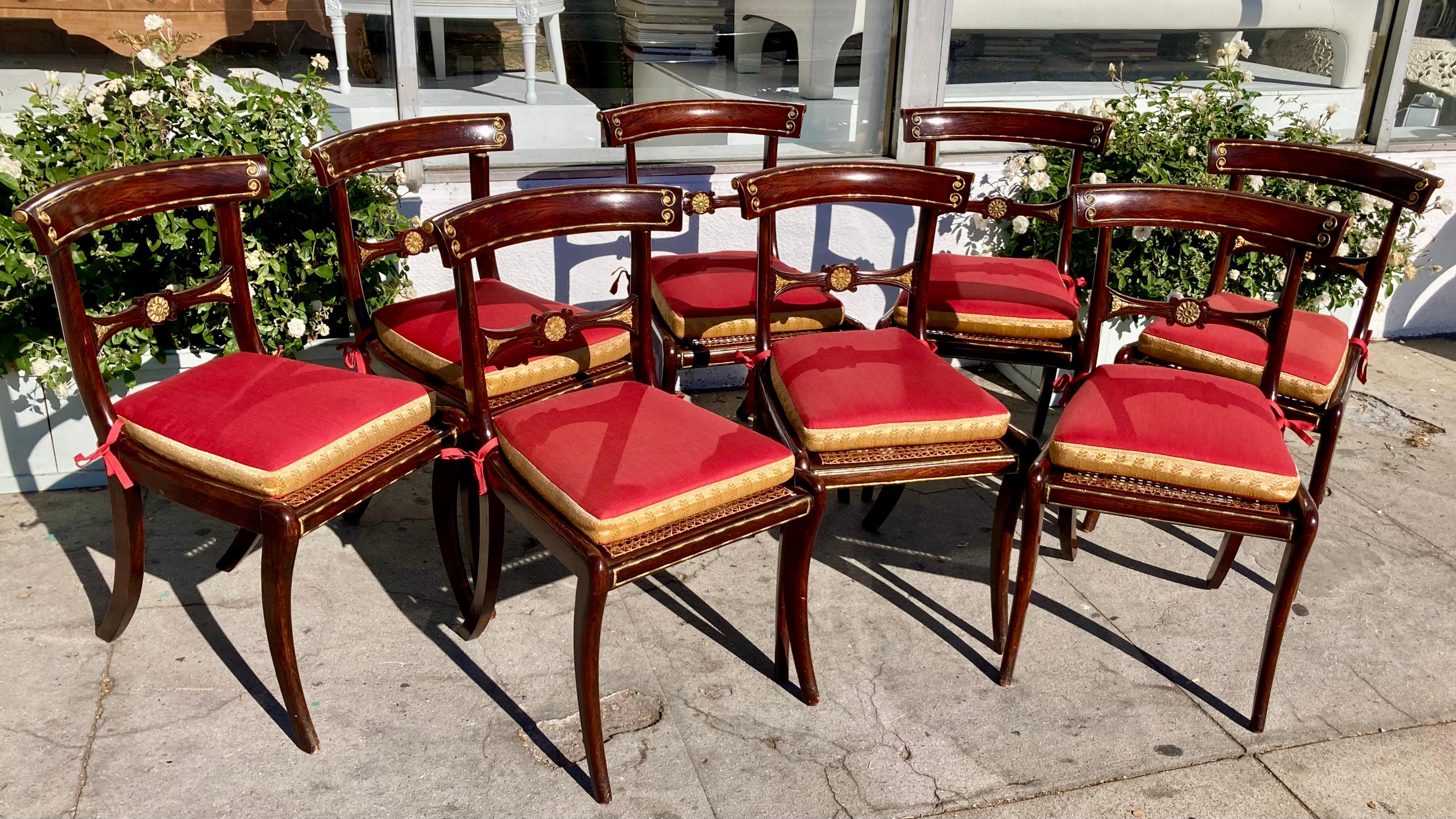 Beautiful set of 8, 19th Century ormolu inset Regency dining chairs with red cushions and gold metal banding. Beautiful cane work under the cushions. These chair are the original finish and are 19th Century from England. Gorgeous ormolu inset